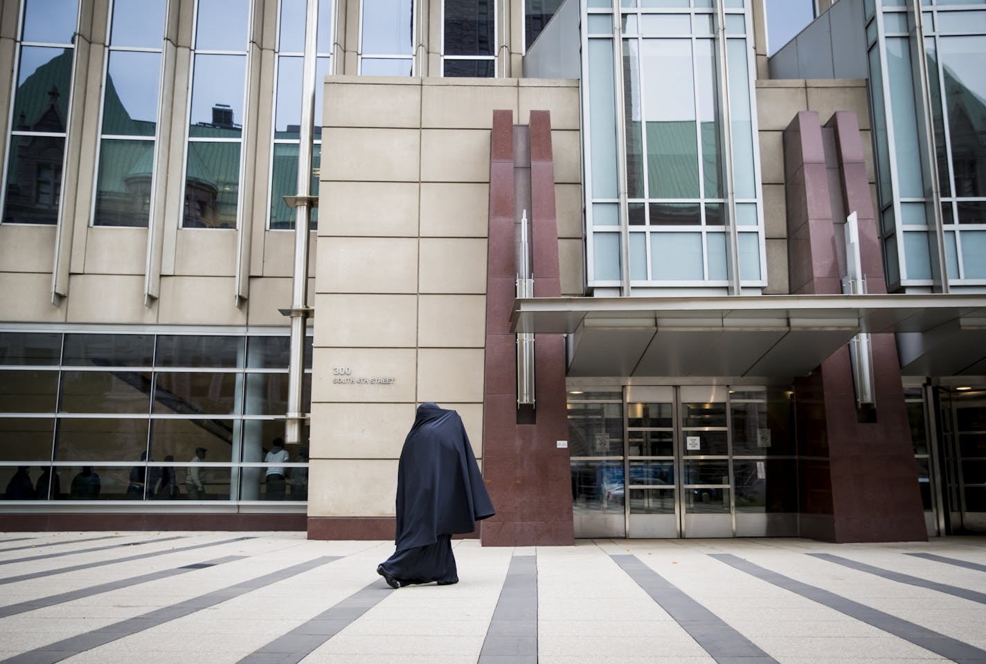 A woman covered her face from the media as she arrived at the Federal Courthouse before the sentencing for three of the nine ISIL recruit defendants on Monday, November 14, 2016, in Minneapolis, Minn.