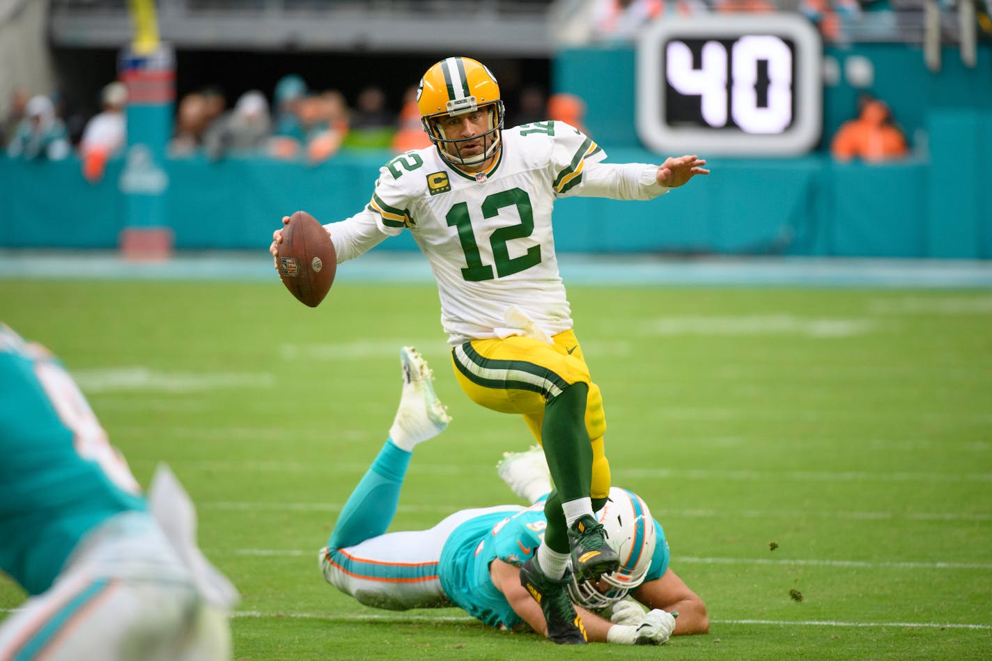 Green Bay Packers quarterback Aaron Rodgers (12) runs with the ball and avoids the tackle by Miami Dolphins defensive tackle Zach Sieler (92) during an NFL football game, Sunday, Dec. 25, 2022, in Miami Gardens, Fla. (AP Photo/Doug Murray)