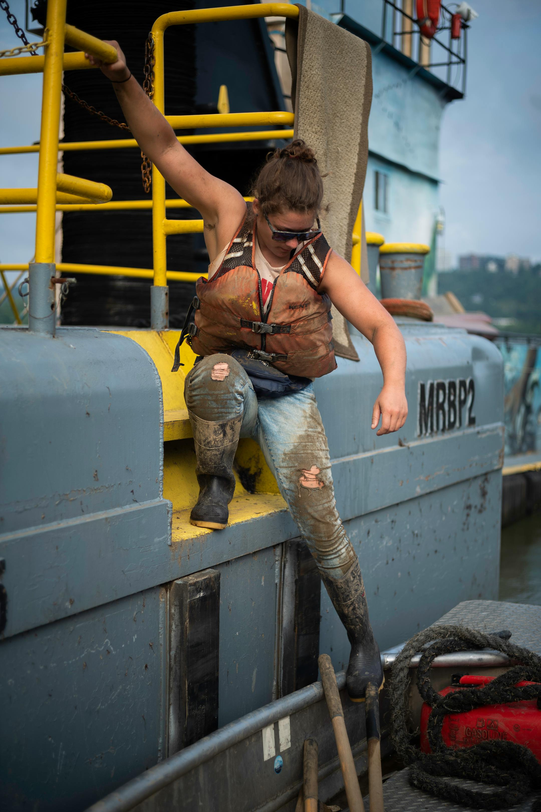 Callie Schafer climbs down into a john boat as they crew heads out for another cleanup on Wednesday, July 14, 2021 in Cincinnati, Ohio.