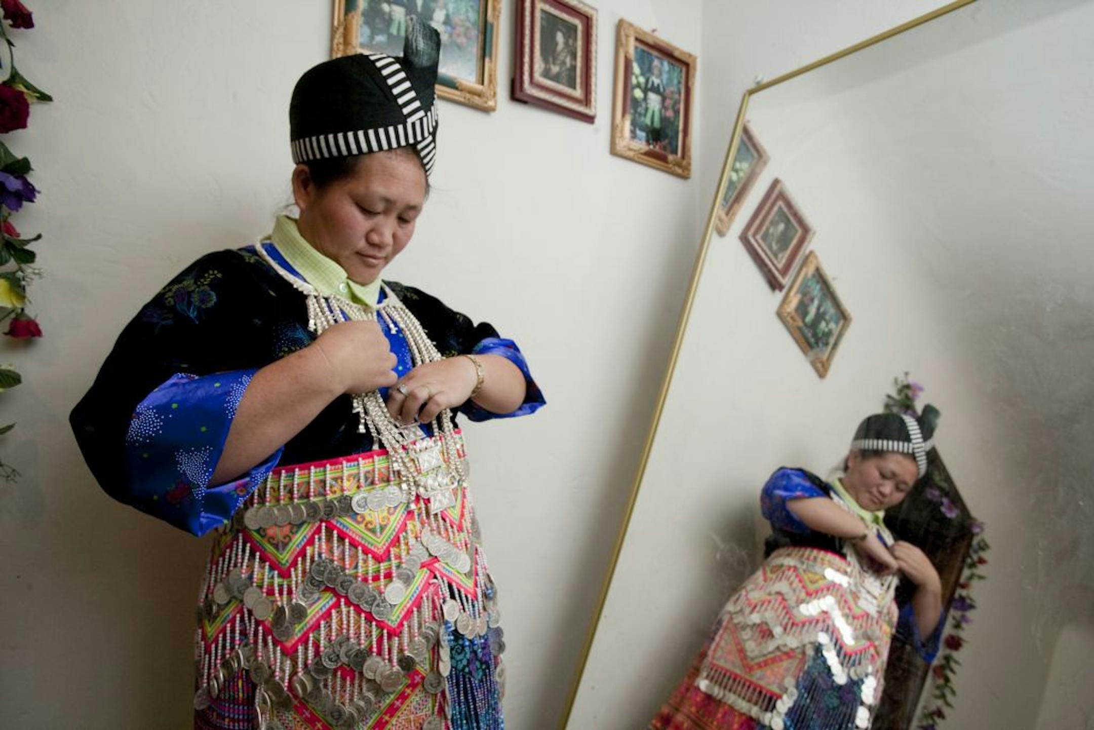 A young Hmong woman dresses herself in traditional clothes for a Hmong New Year celebration in Fresno, Calif.