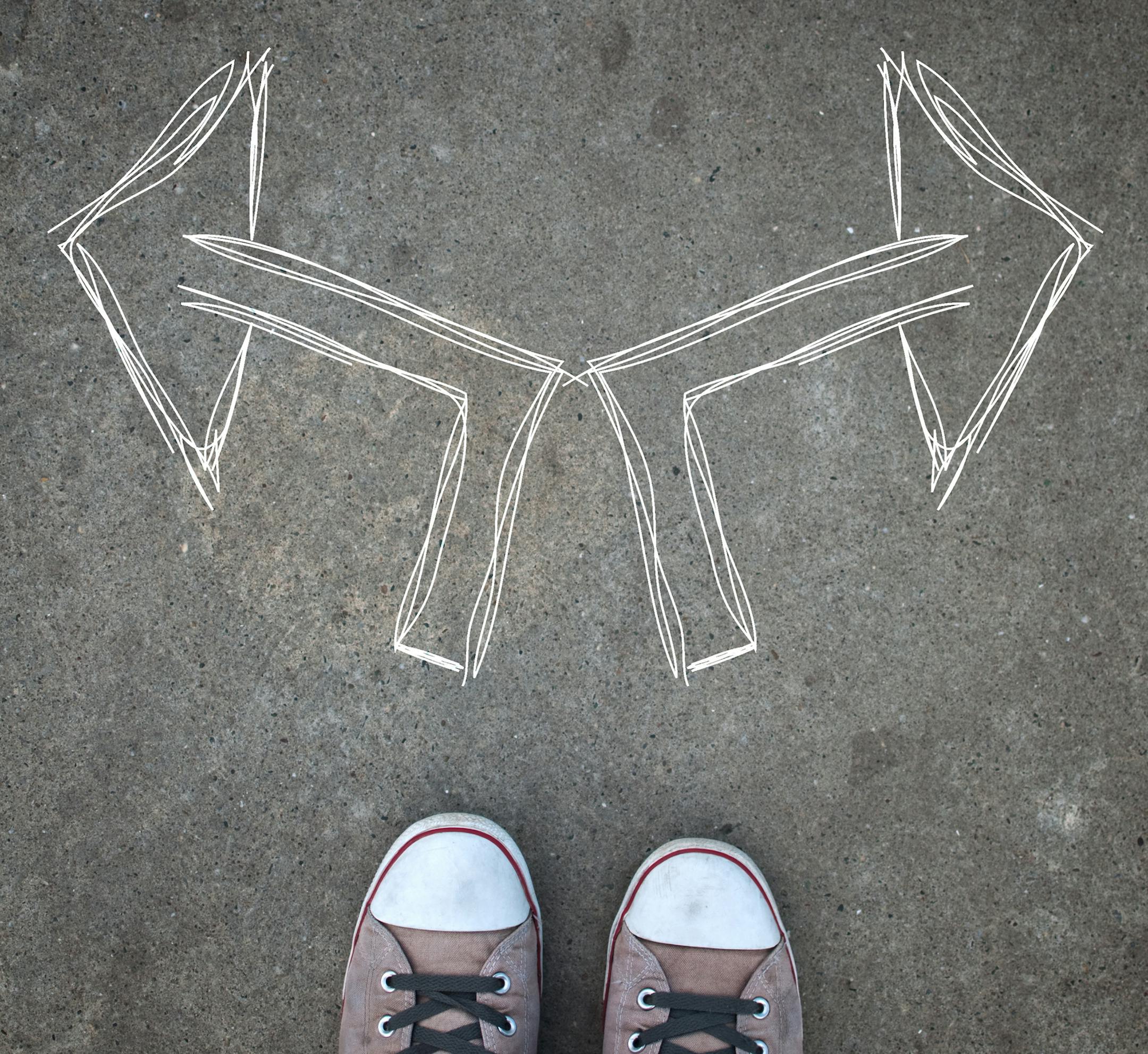 Male sneakers on the asphalt road with drawn direction arrow