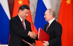 Russian President Vladimir Putin, right, and Chinese President Xi Jinping shake hands as they exchange documents during a signing ceremony following t