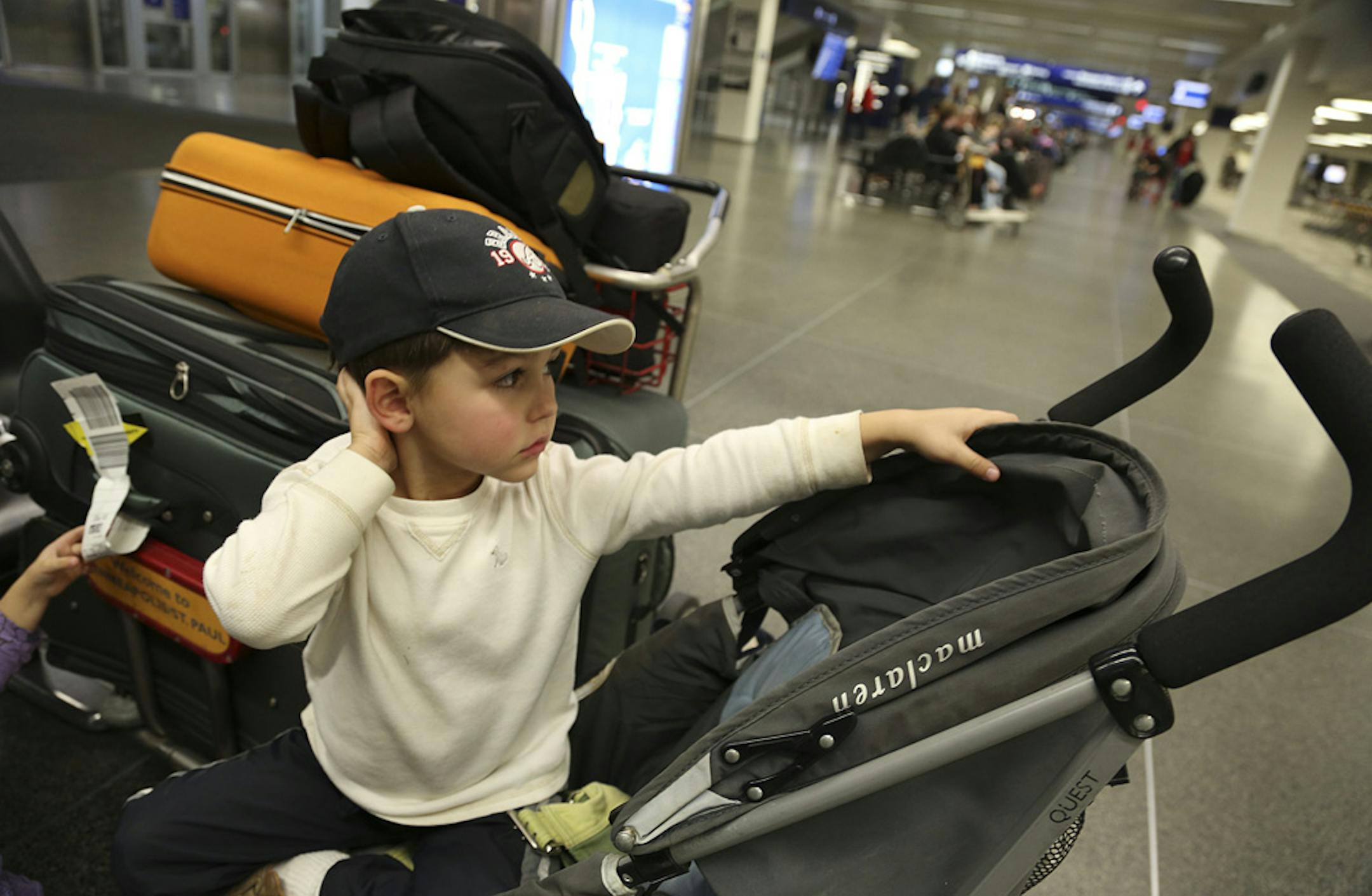 Elias Coffey, 4, of Atlanta, sat with his family's bags as he waited for his grandparents to arrive from California at MSP Airport.