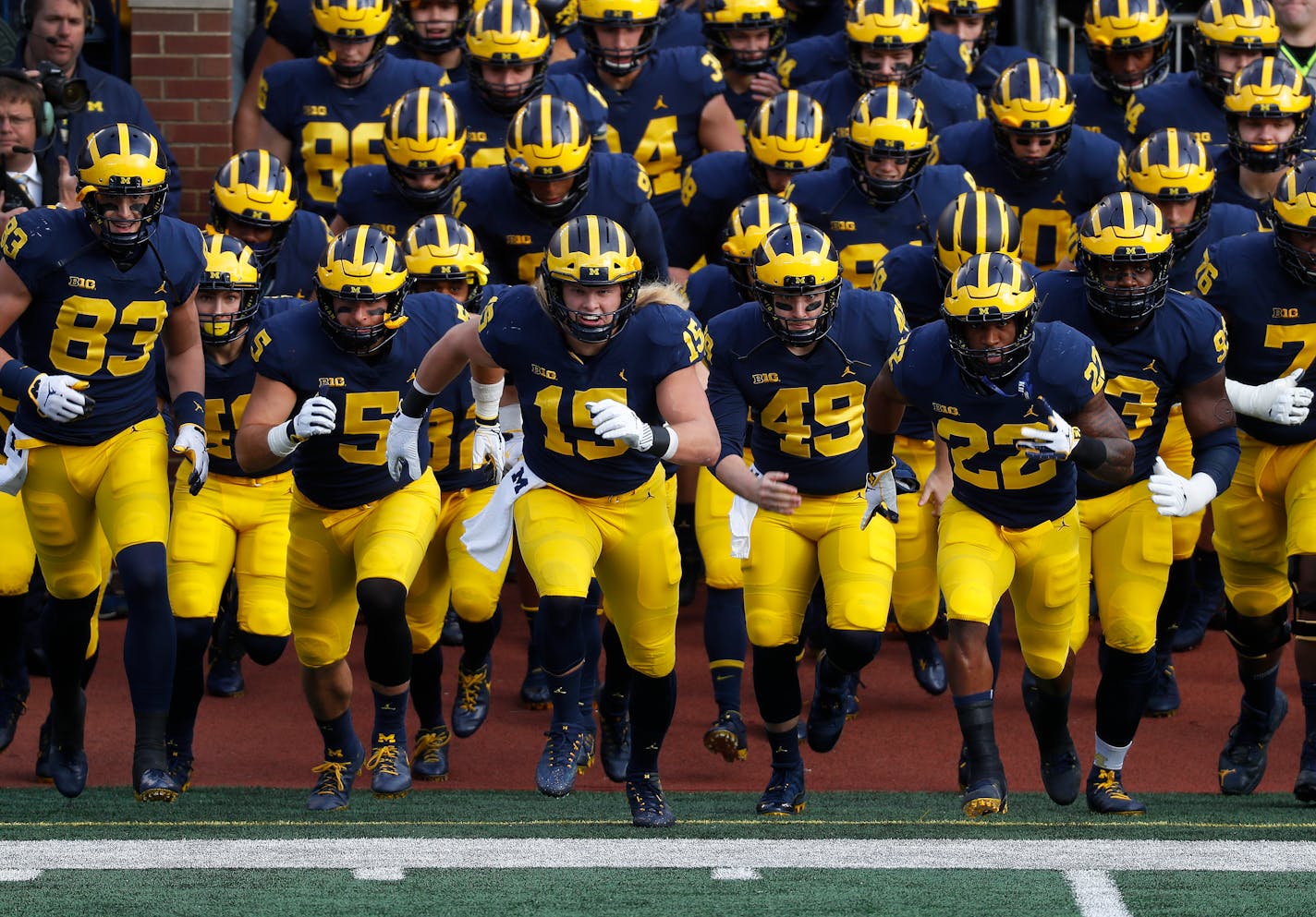 Michigan defensive lineman Chase Winovich (15) leads the team onto the field