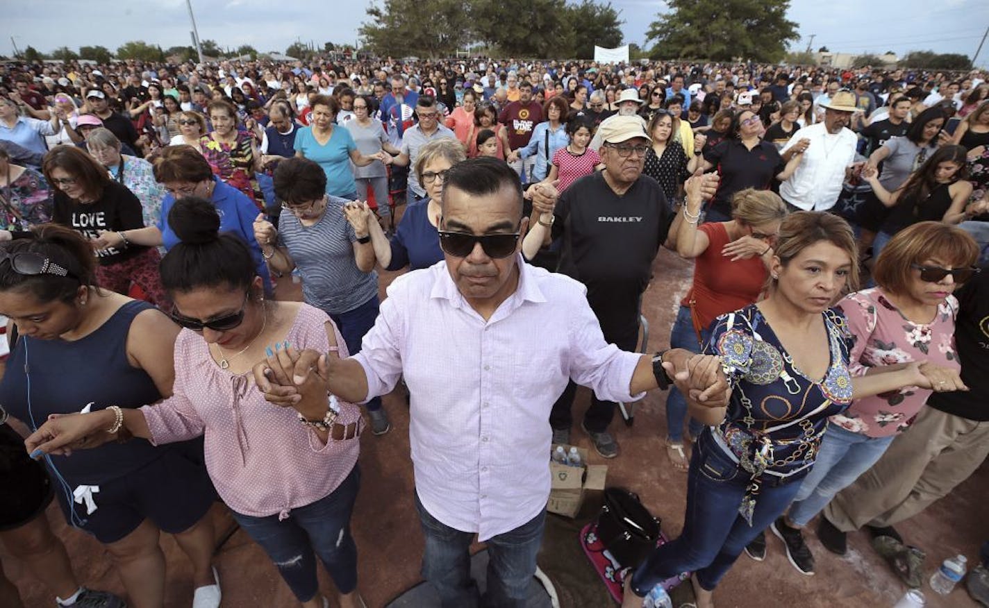 FILE - In this Aug. 4, 2019, file photo, people join hands and pray during the Hope Border Institute prayer vigil in El Paso, Texas, a day after a mass shooting at a Walmart store. The largely Hispanic city of El Paso has deep roots in Catholicism and religion in general. After the massacre that left more than 20 dead and many others injured, residents are turning to their faith to get through these times.