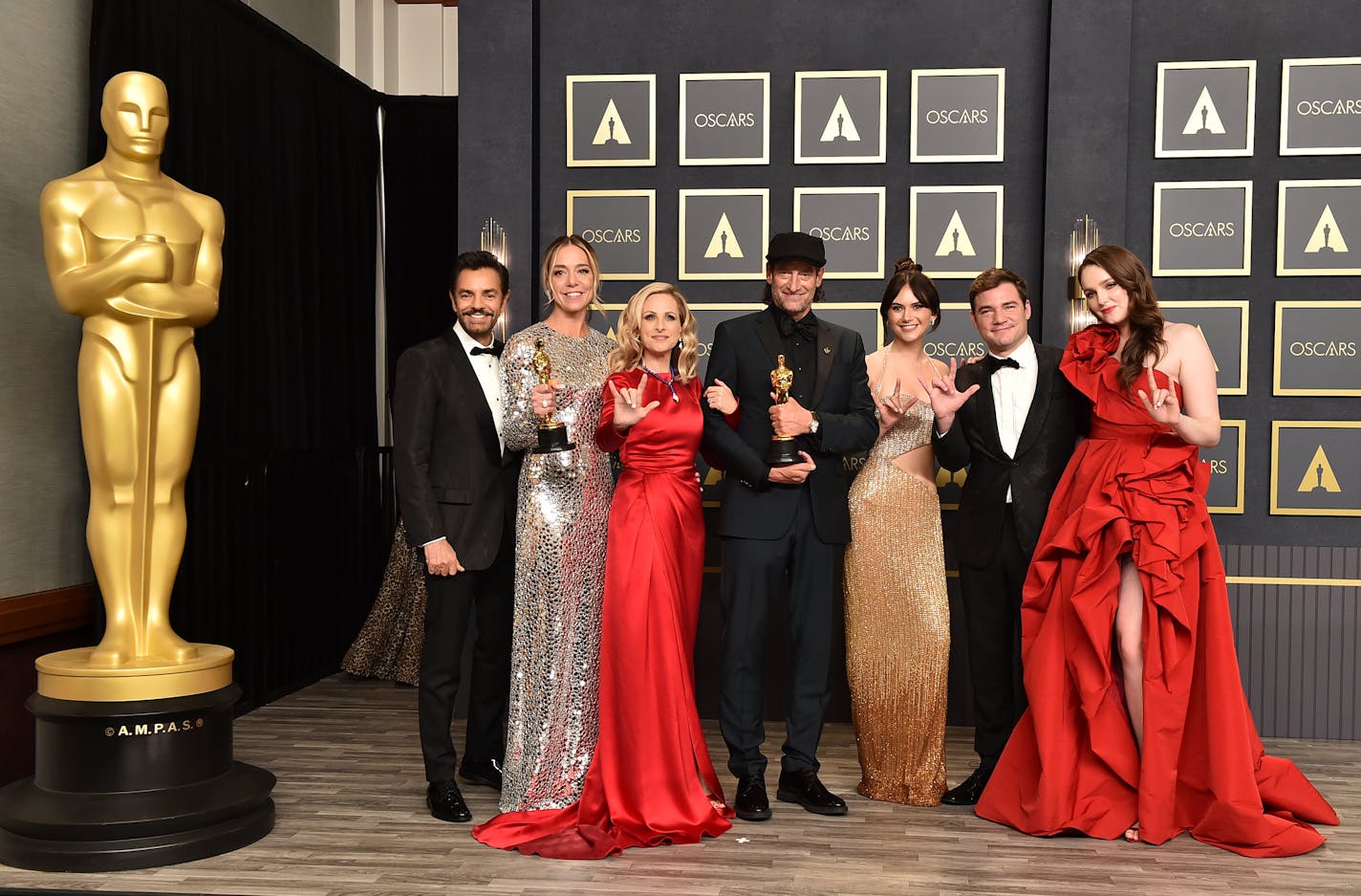 Eugenio Derbez, from left, Sian Heder, Marlee Matlin, Troy Kotsur, Emilia Jones, Daniel Durant, and Amy Forsyth, winners of the award for best picture for "CODA," pose in the press room while signing "I love you" at the Oscars on Sunday, March 27, 2022, at the Dolby Theatre in Los Angeles. (Photo by Jordan Strauss/Invision/AP)