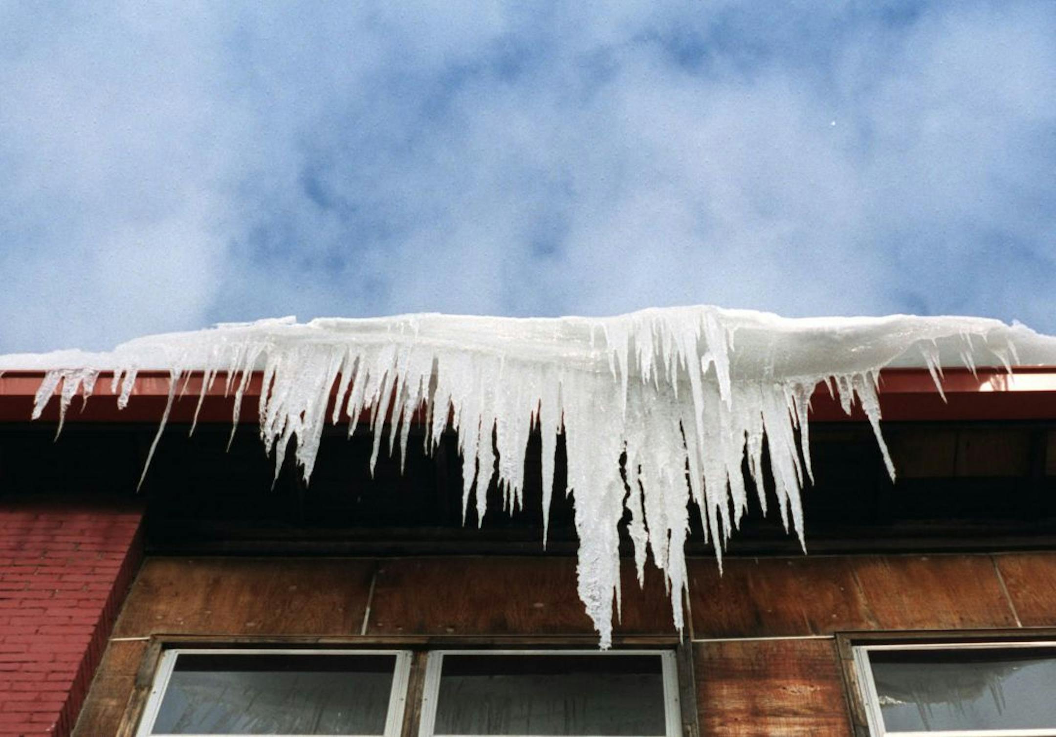 As clouds roll across a blue sky icicles drip as they cling to the roof of a house on Park Ave. near 9th Street Wednesday afternoon.