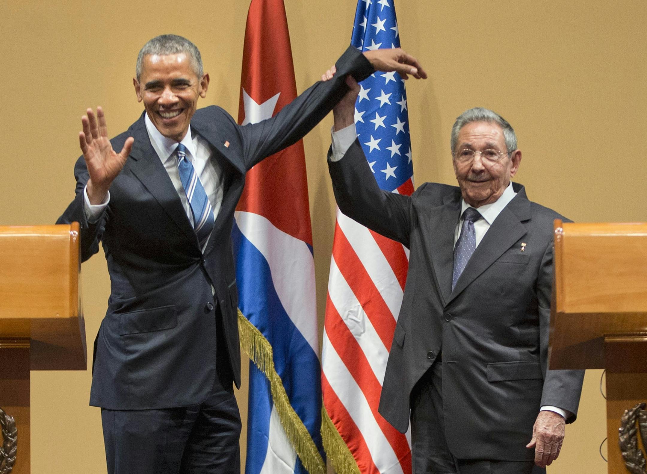 Cuban President Raul Castro lifts up the arm of President Barack Obama at the conclusion of their joint news conference at the Palace of the Revolution, Monday, March 21, 2016 in Havana, Cuba.