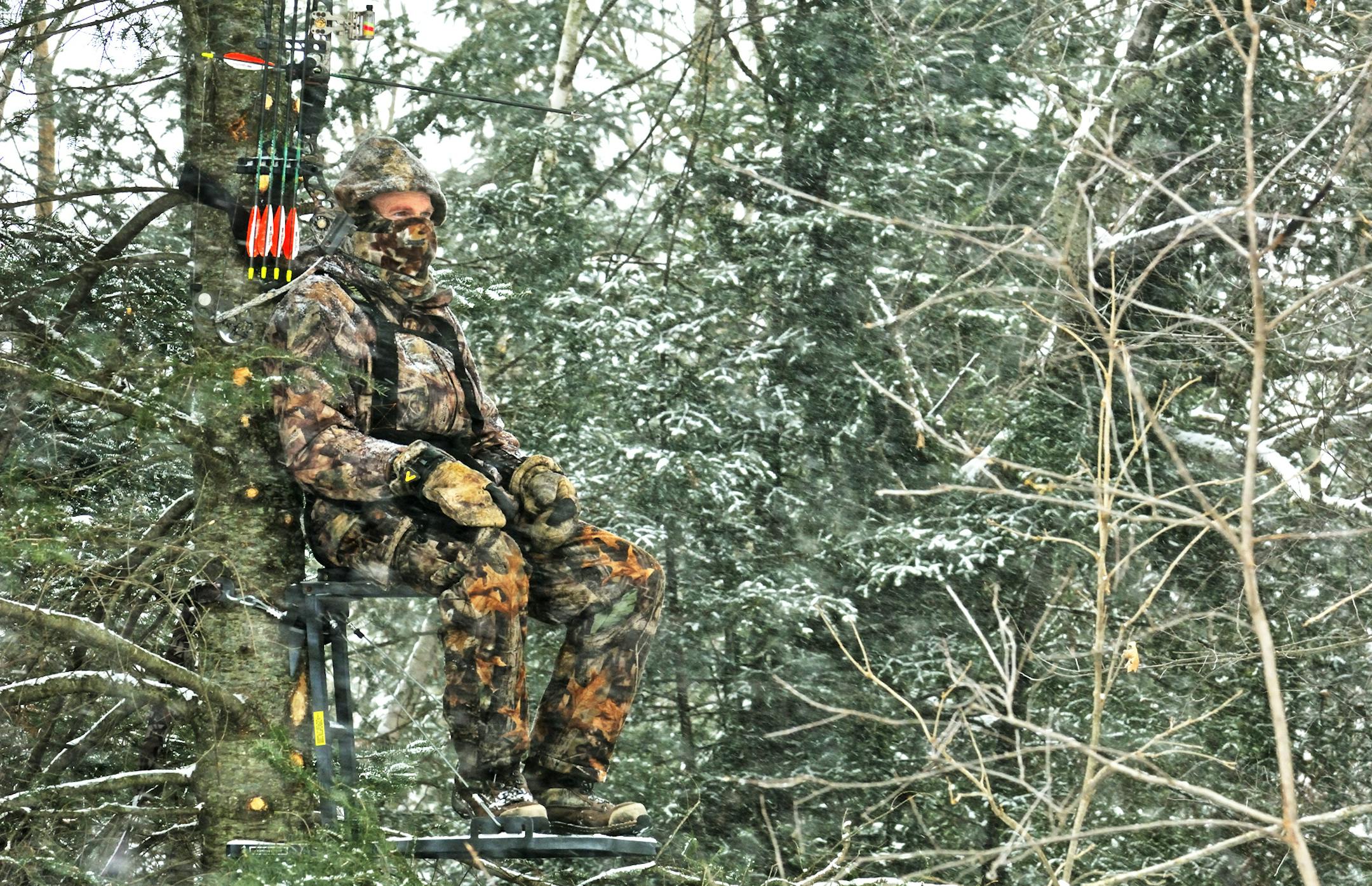 Keeping warm while waiting for a late-season deer is critical. Not only is this hunter smartly dressed, he is avoiding cold fingers by hanging his bow within arm's reach. Photo by Bill Marchel