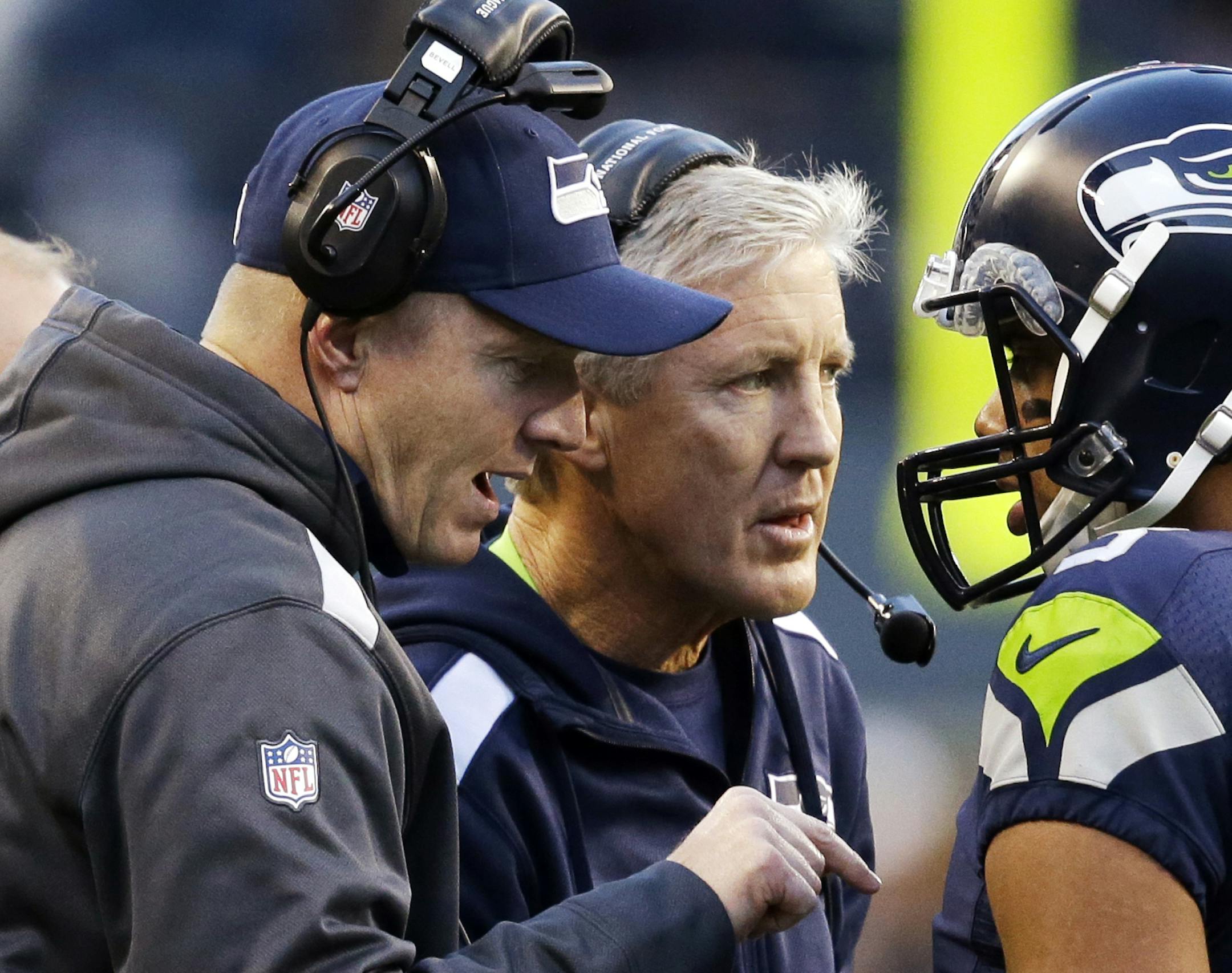 Seattle Seahawks quarterback Russell Wilson (3) talks with head coach Pete Carroll, center, and offensive coordinator Darrell Bevell before Wilson's final play against the Tampa Bay Buccaneers in overtime in an NFL football game Sunday, Nov. 3, 2013, in Seattle. The Seahawks won 27-24 on a field goal in overtime. (AP Photo/Elaine Thompson) ORG XMIT: MIN2013111517164775