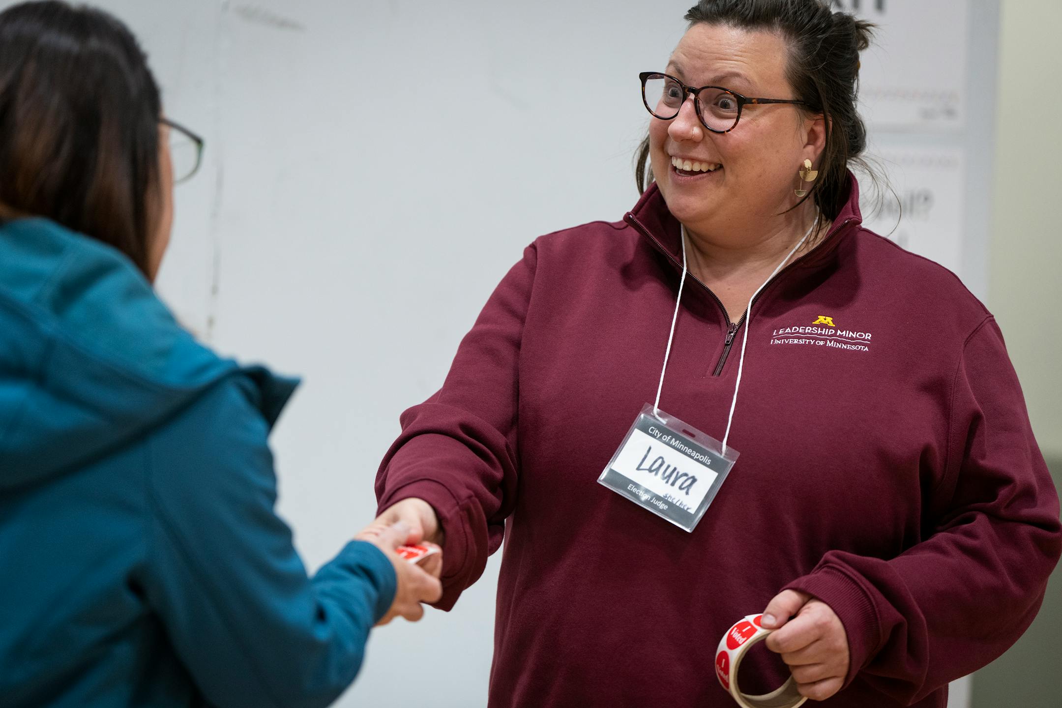 Election judge Laura Wiesner gives out stickers to voters at Hiawatha Collegiate High School on Election Day in Ward 12 of Minneapolis.