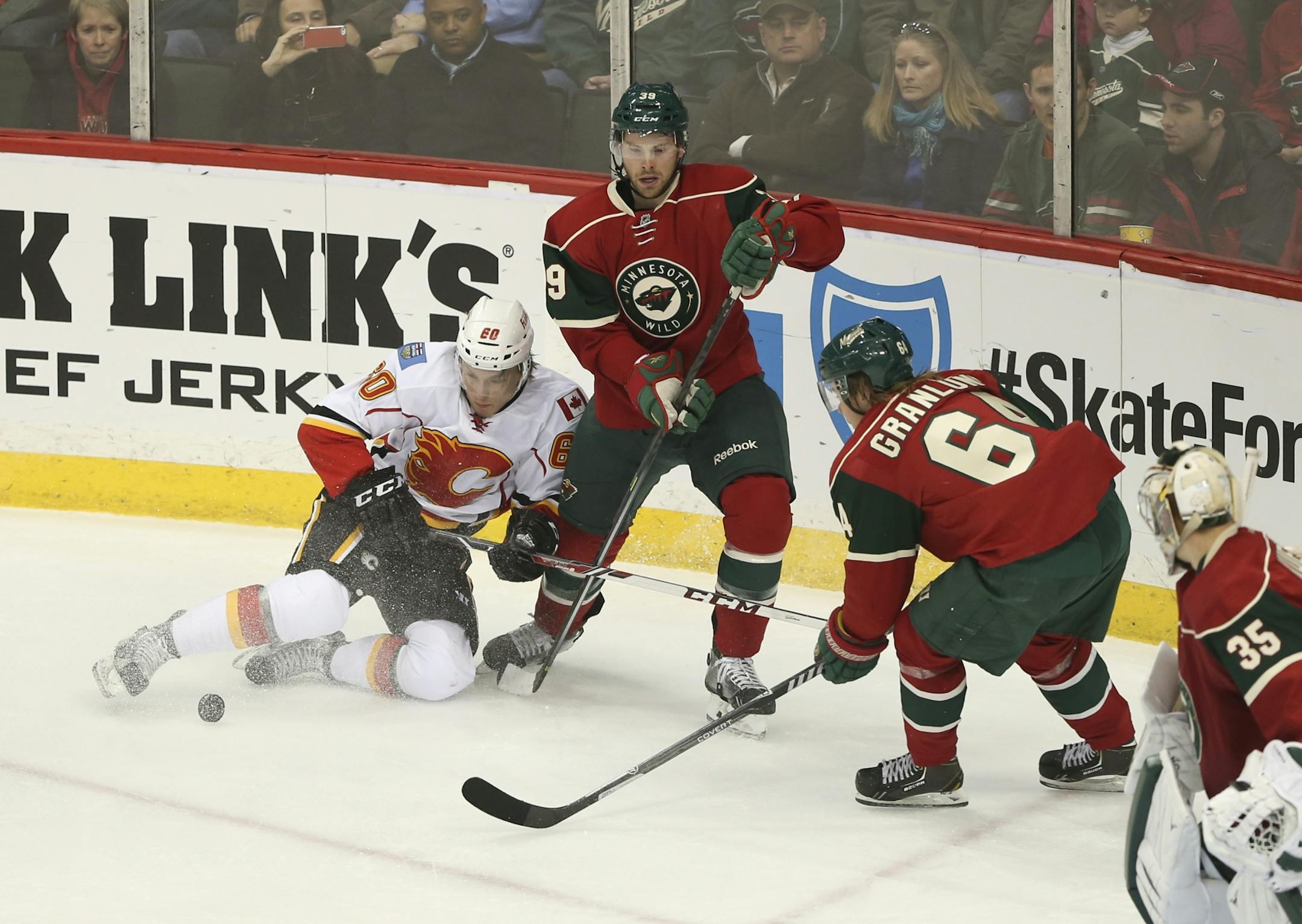 The Minnesota Wild faced the Calgary Flames in an NHL hockey game Monday night, March 3, 2014 at Xcel Energy Center in St. Paul. Calgary's Markus Granlund (60) and his brother, the Wild's Mikael Granlund (64) vied for the puck on either side of Minnesota's Nate Prosser in the second period.
