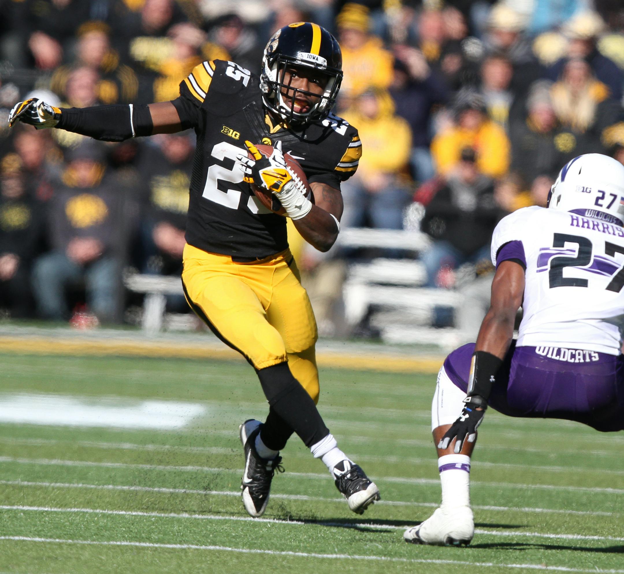 Iowa running back Akrum Wadley (25) tries avoid Northwestern cornerback Matthew Harris (27) during the second half of an NCAA college football game, Saturday, Nov. 1, 2014, in Iowa City, Iowa. (AP Photo/Justin Hayworth)