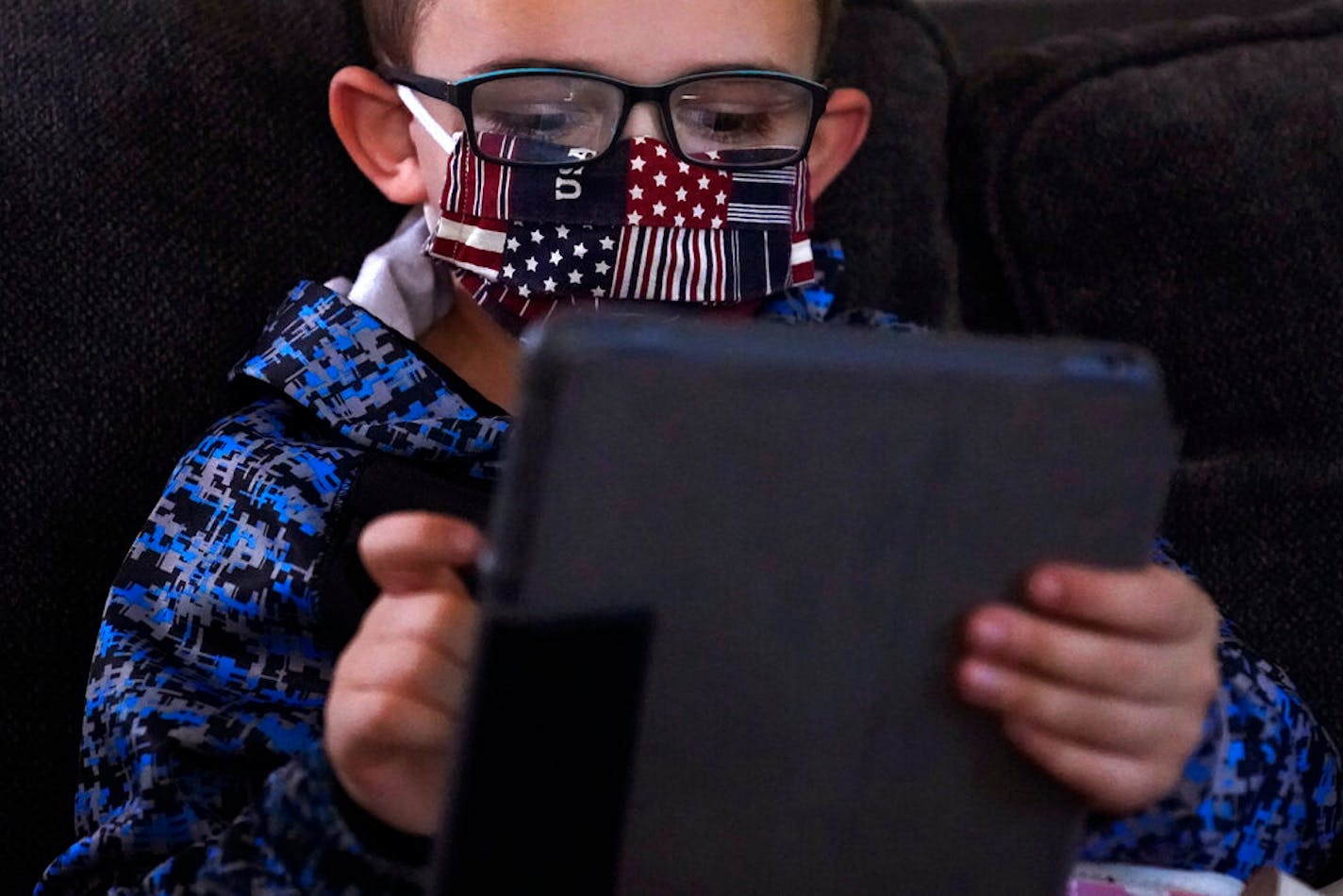 Kindergarten student Wyatt works on a tablet with his mom, Christi Brouder, in a makeshift classroom in the living room at the family home, Wednesday, Oct. 14, 2020, in Haverhill, Mass.