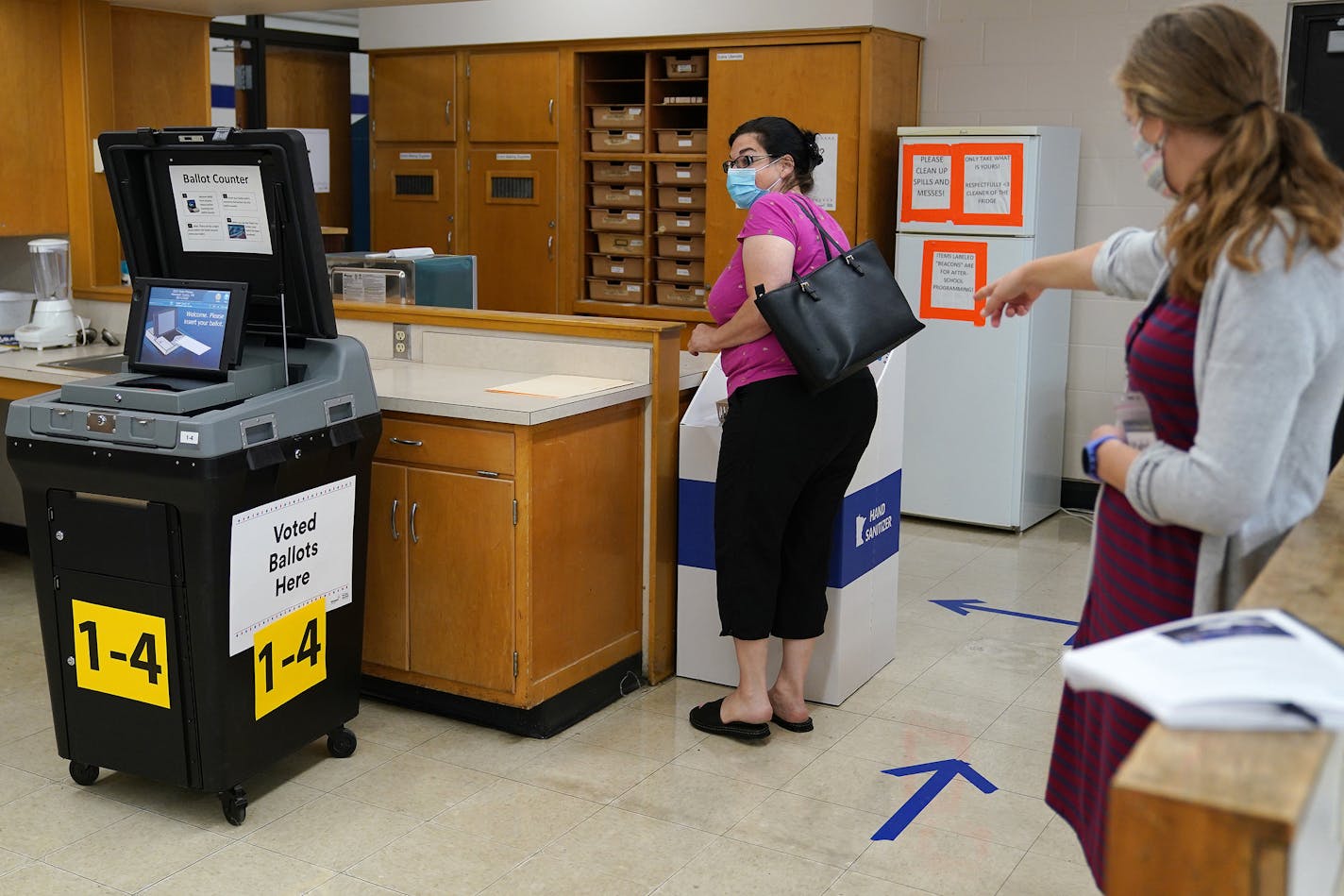 Election judge Katelyn Engel, right, directed Dolores Ojard where she could get a sticker after voting Tuesday morning at Northeast Middle School in Minneapolis.