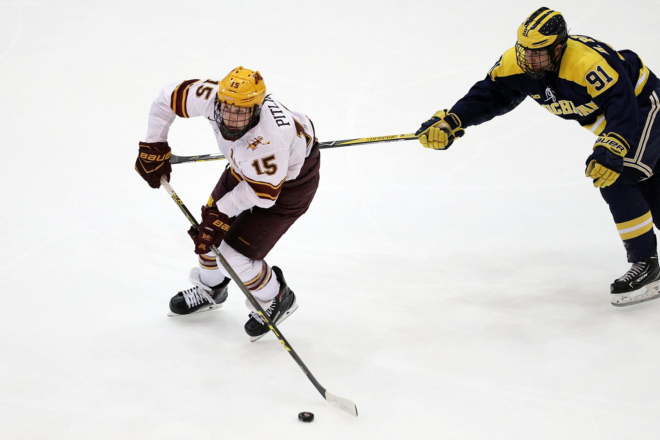 Michigan Wolverines forward Nick Pastujov (91) reached out with his stick as Minnesota Golden Gophers forward Rem Pitlick (15) skated with the puck in the third period.