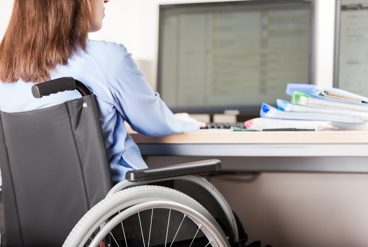 Disabled young business woman person sitting wheelchair working office desk computer