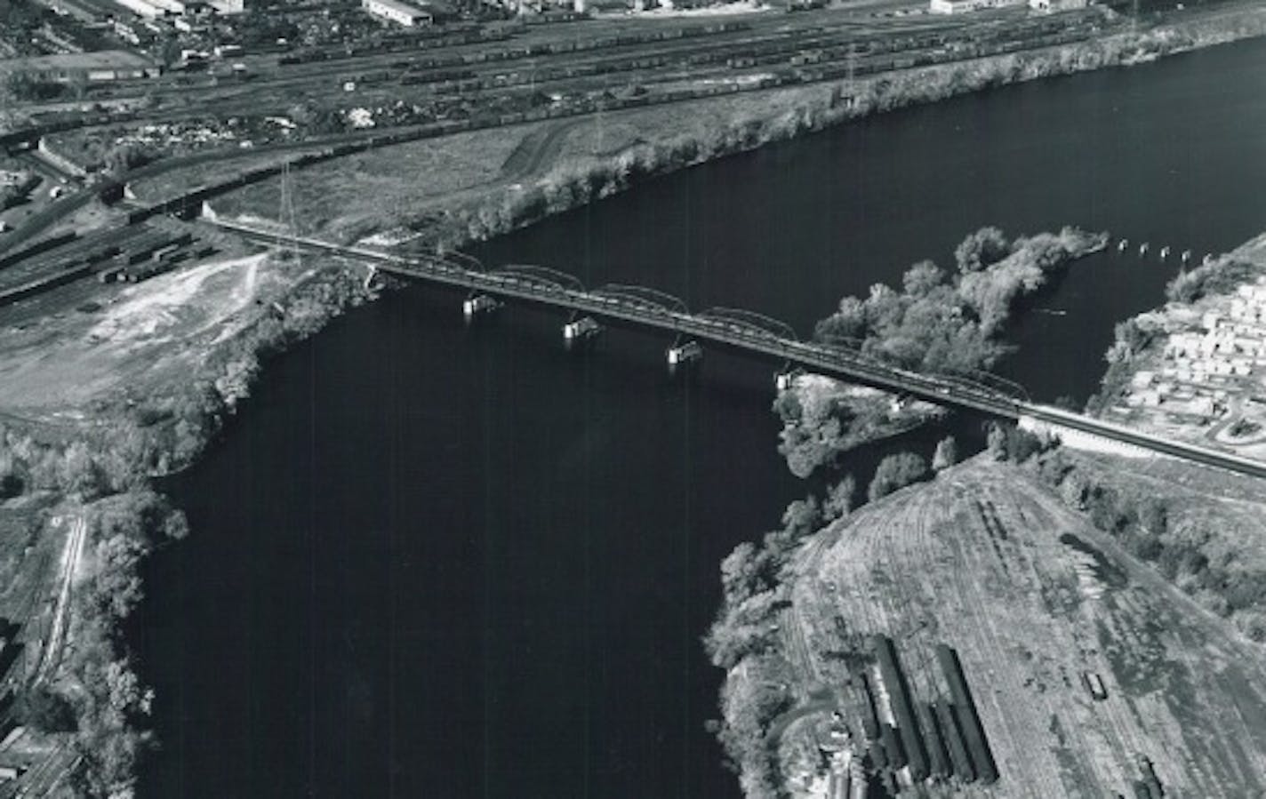 Hall's Island as it appeared before the channel separating it from the mainland was filled in the mid-1960s. The old Plymouth Avenue Bridge bisects the island, connecting a riverfront dominated by railroads.