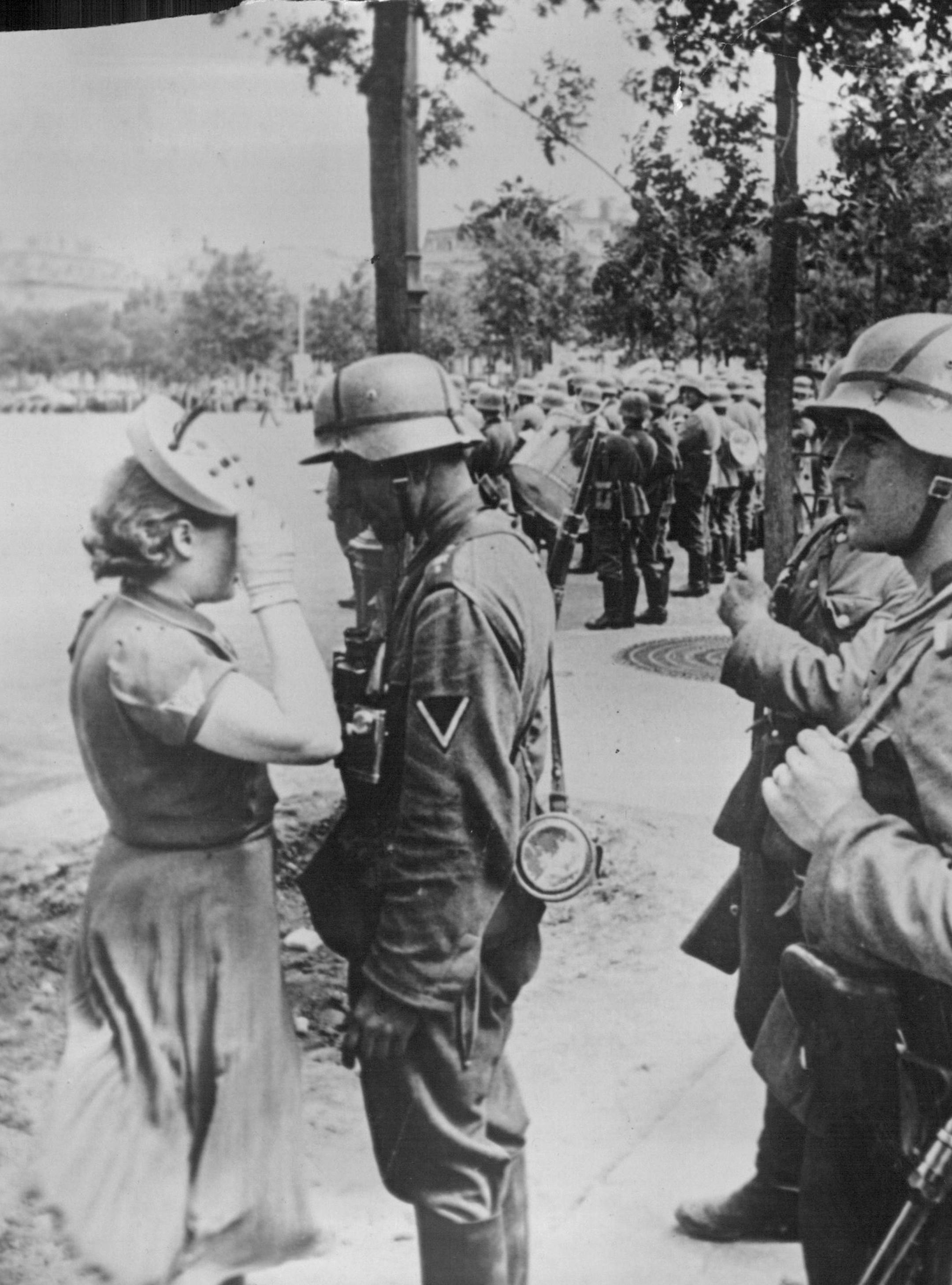 July 9, 1940 Permission of a German officer is required before Frenchmen in Paris are permitted to do anything out of the ordinary. Pis here passed by the German censor, shows French girl saluting a Nazi officer before speaking to him.