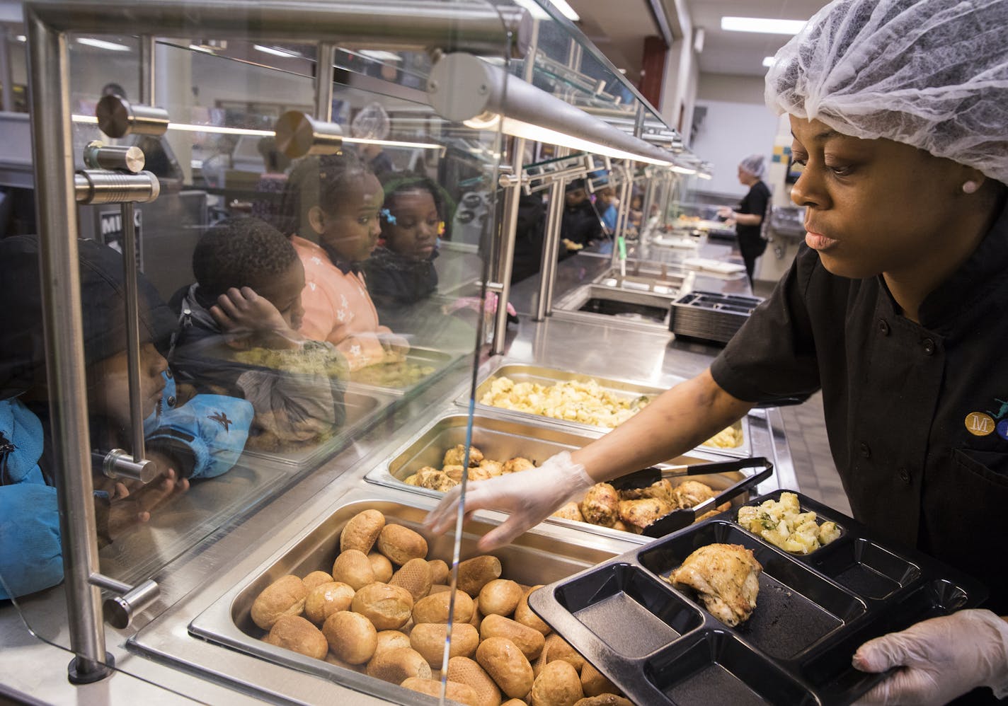 Food service assistant Arica Burgess serves chicken with potatoes and rolls for lunch.