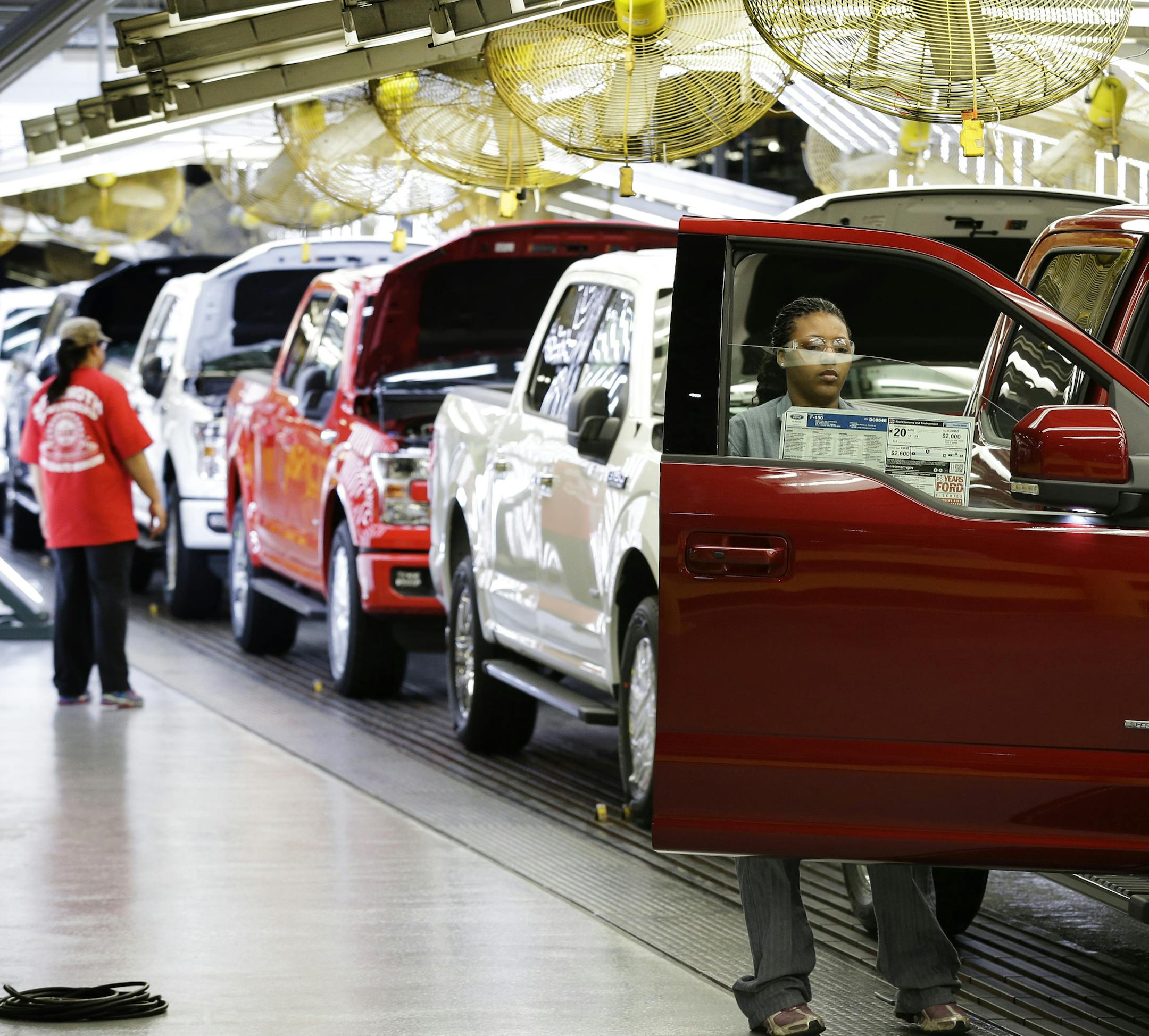 In this March 13, 2015 photo, workers inspect new 2015 aluminum-alloy body Ford F-150 trucks at the company's Kansas City Assembly Plant in Claycomo, Mo. Ford reports quarterly financial results on Tuesday, July 28, 2015. (AP Photo/Charlie Riedel)