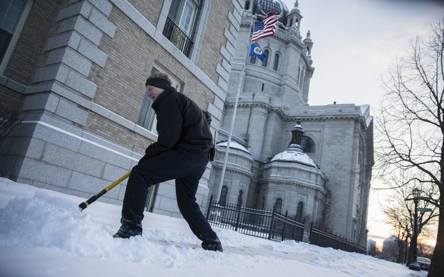 Paul Storms, a maintenance worker with the Cathedral of St. Paul, clears the sidewalks before the 7:30 a.m. mass.