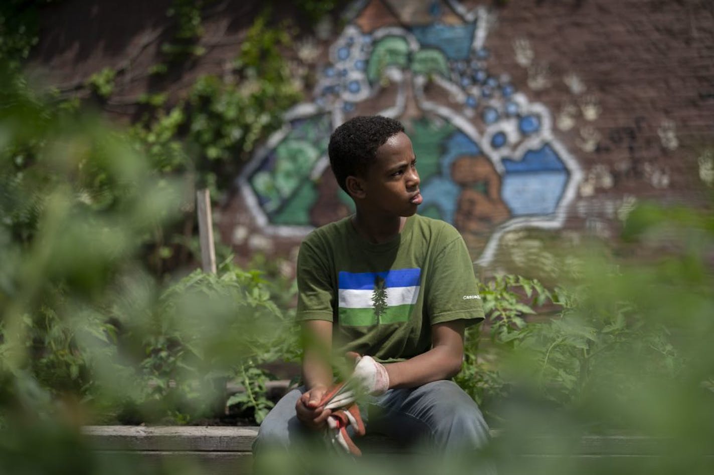 Guled Ased, 14, put gloves on at the Urban Oasis Community garden in north Minneapolis on Wednesday.