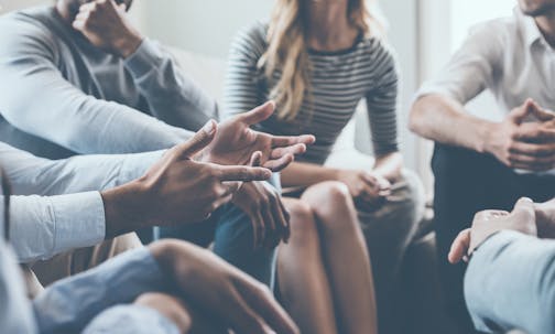 Close-up of people communicating while sitting in circle and gesturing