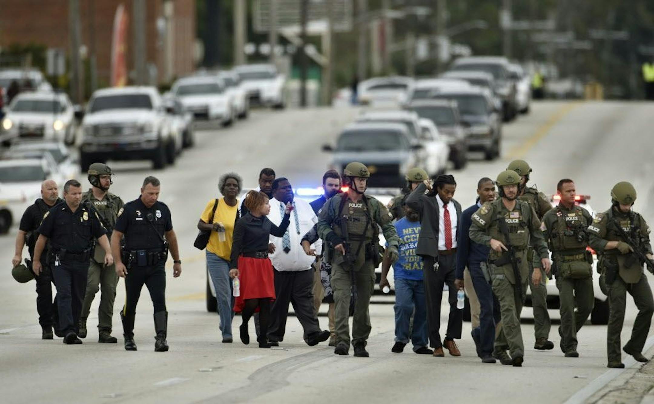 Police officers escort hostages safely across Edgewood Avenue West after a gunman held them during an attempted robbery at Community First Credit Union Thursday, Dec. 1, 2016, in Jacksonville, Fla.
