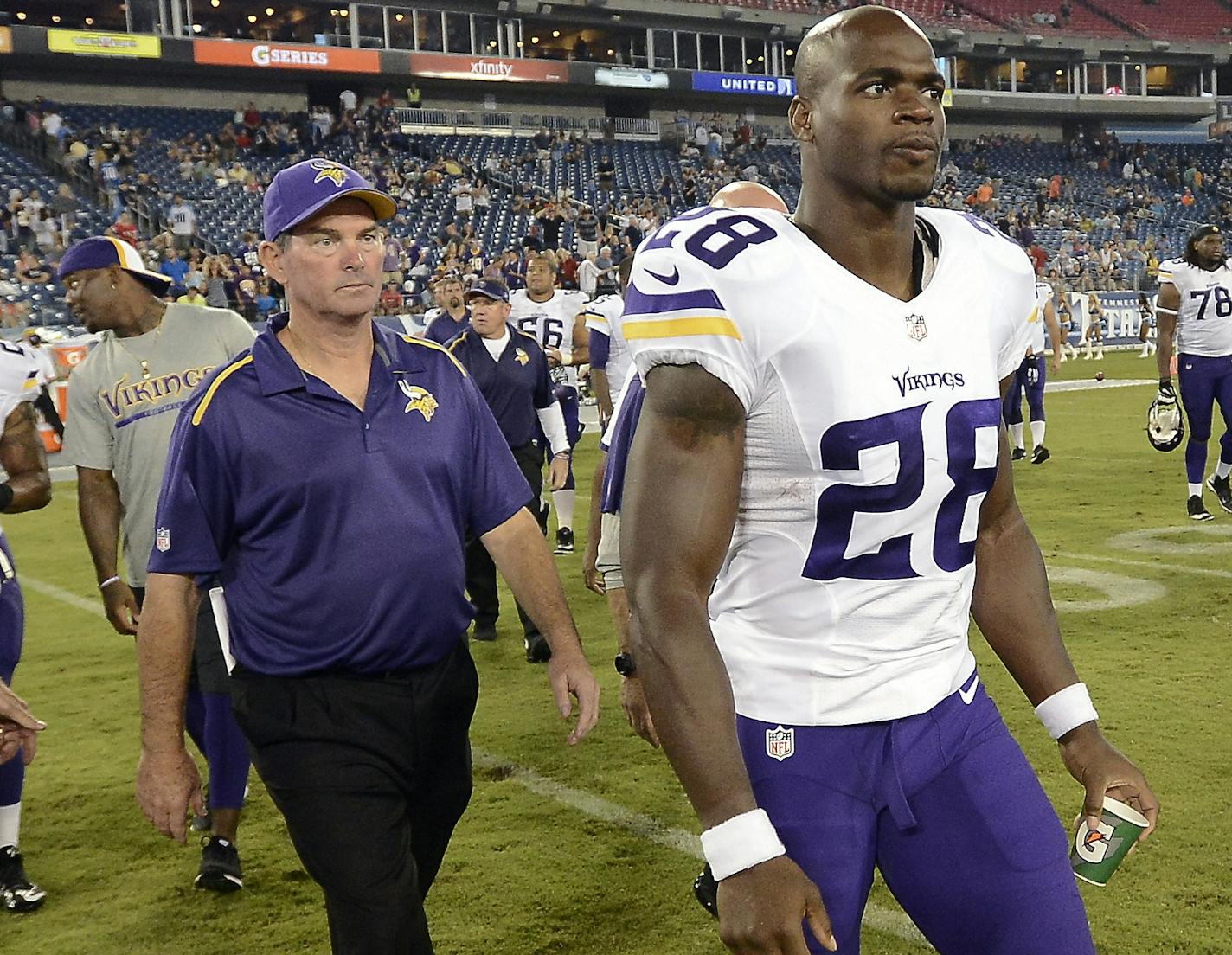 Minnesota Vikings running back Adrian Peterson (28) and head coach Mike Zimmer, left, walk onto the field after beating the Tennessee Titans 19-3 in a preseason NFL football game Thursday, Aug. 28, 2014, in Nashville, Tenn. (AP Photo/Mark Zaleski) ORG XMIT: MIN2014091218350508