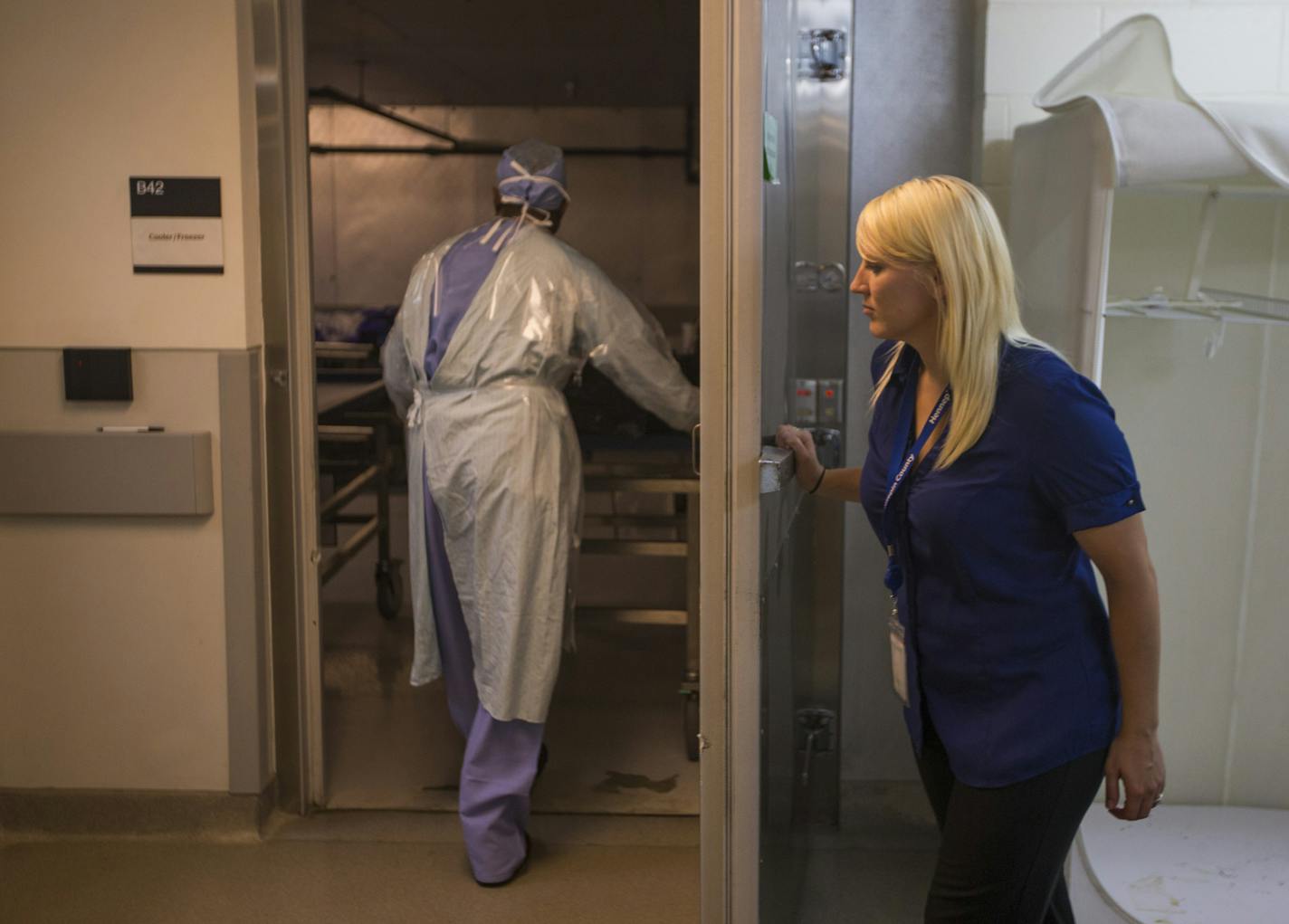 Hennepin County medical examiner's office investigator Raschael Ellering held the door for a person wheeling a body to the cooling area where they keep bodies after autopsies before they go to the funeral home or until they are identified at Hennepin County Medical Examiners office on Friday, August 14, 2015 in Minneapolis, Minn. ] RENEE JONES SCHNEIDER &#x2022; reneejones@startribune.com