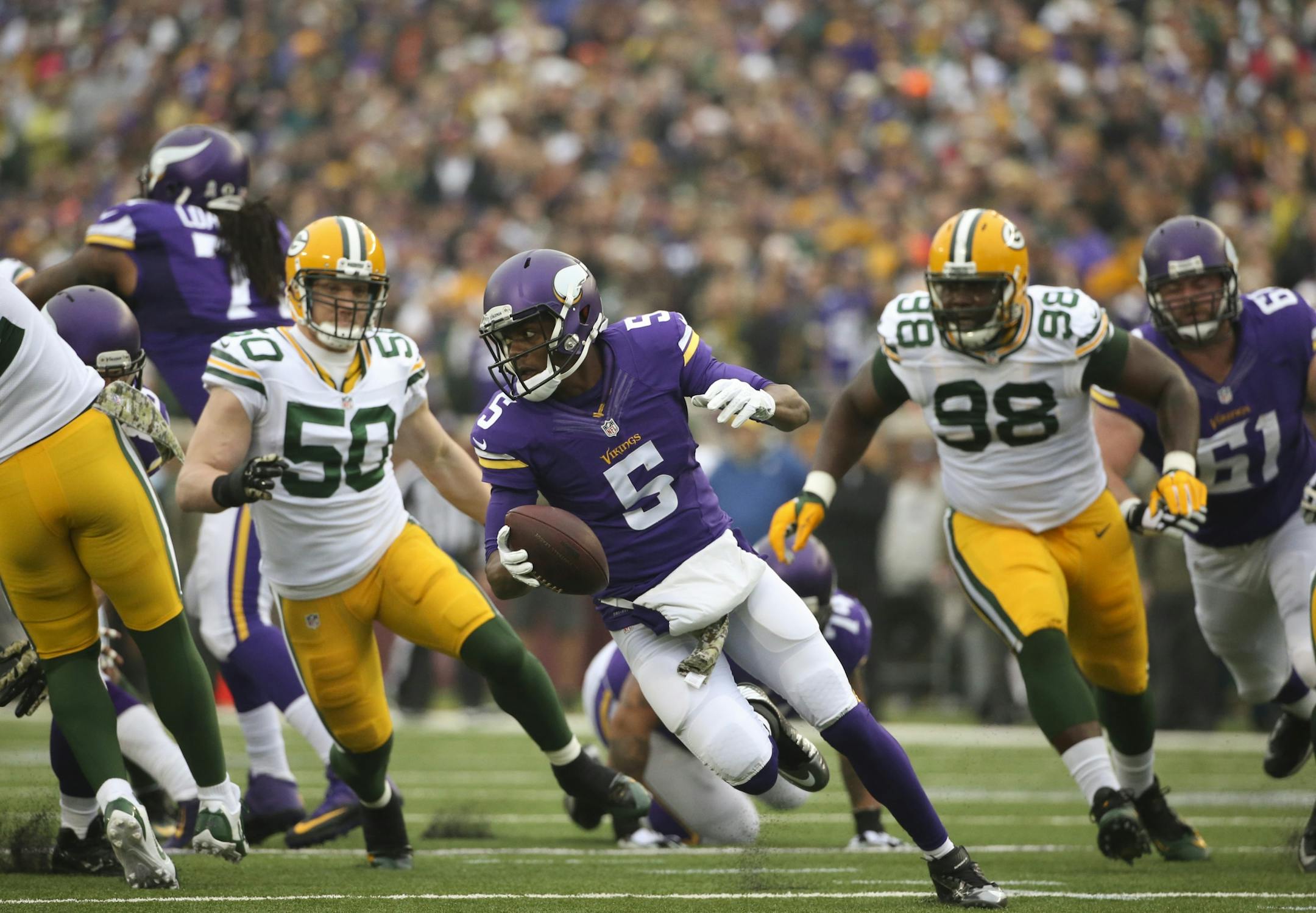 Minnesota Vikings quarterback Teddy Bridgewater scrambled away from Green Bay Packers inside linebacker A.J. Hawk (50) Green Bay Packers nose tackle Letroy Guion (98) in the first quarter Sunday afternoon at TCF Bank Stadium in Minneapolis.