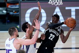 Brooklyn Nets' Caris LeVert (22) looks to pass the ball as Sacramento Kings' Alex Len, left, and Harrison Barnes defend during the second half of an N