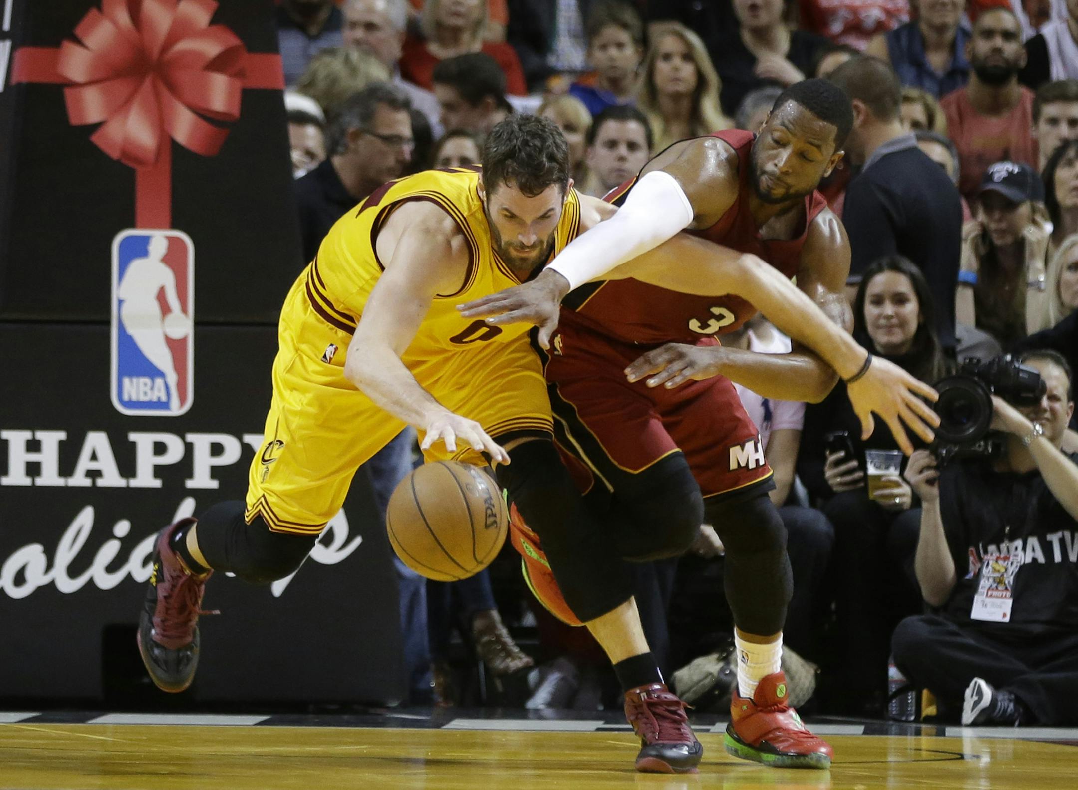 Cleveland Cavaliers forward Kevin Love (0) is defended by Miami Heat guard Dwyane Wade (3) during the first half of an NBA basketball game, Thursday, Dec. 25, 2014, in Miami. (AP Photo/Lynne Sladky)