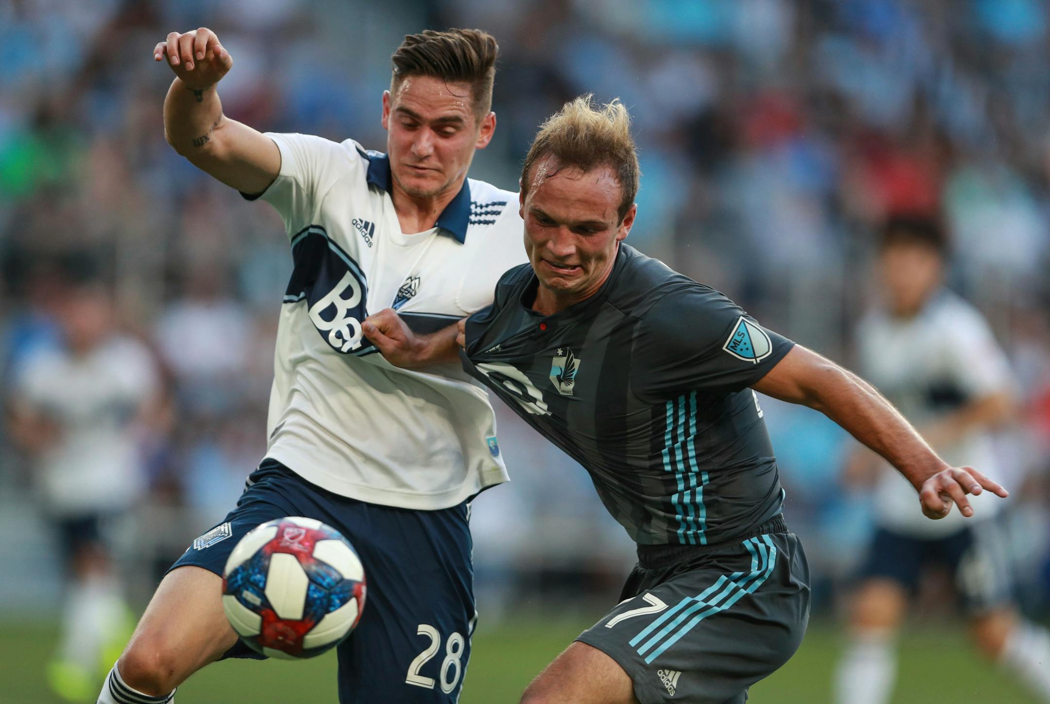 Vancouver defenseman Jake Nerwinski jostles with Minnesota United midfielder Collin Martin for the ball during the first half