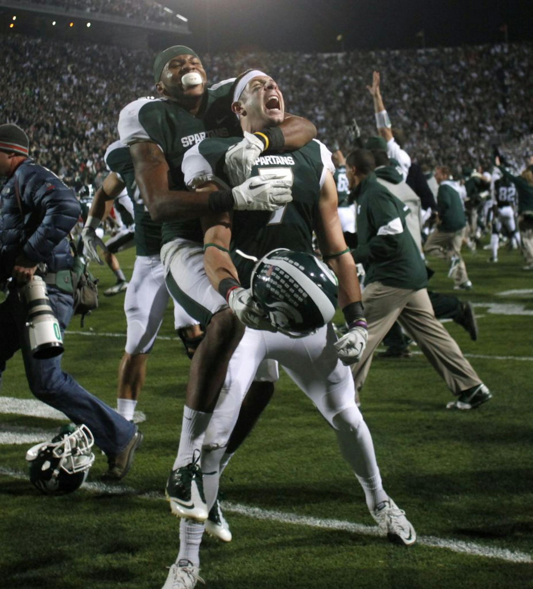 Michigan State's Keith Nichol, center, and B.J. Cunningham celebrate following a 37-31 win over Wisconsin in an NCAA college football game, Saturday, Oct. 22, 2011, in East Lansing, Mich. Nichol caught the game-winning pass on the final play.