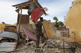 A Somali soldier stands near a destroyed building outside the police traffic station in Mogadishu, Somalia, Monday, May, 9, 2016. A Somali police offi
