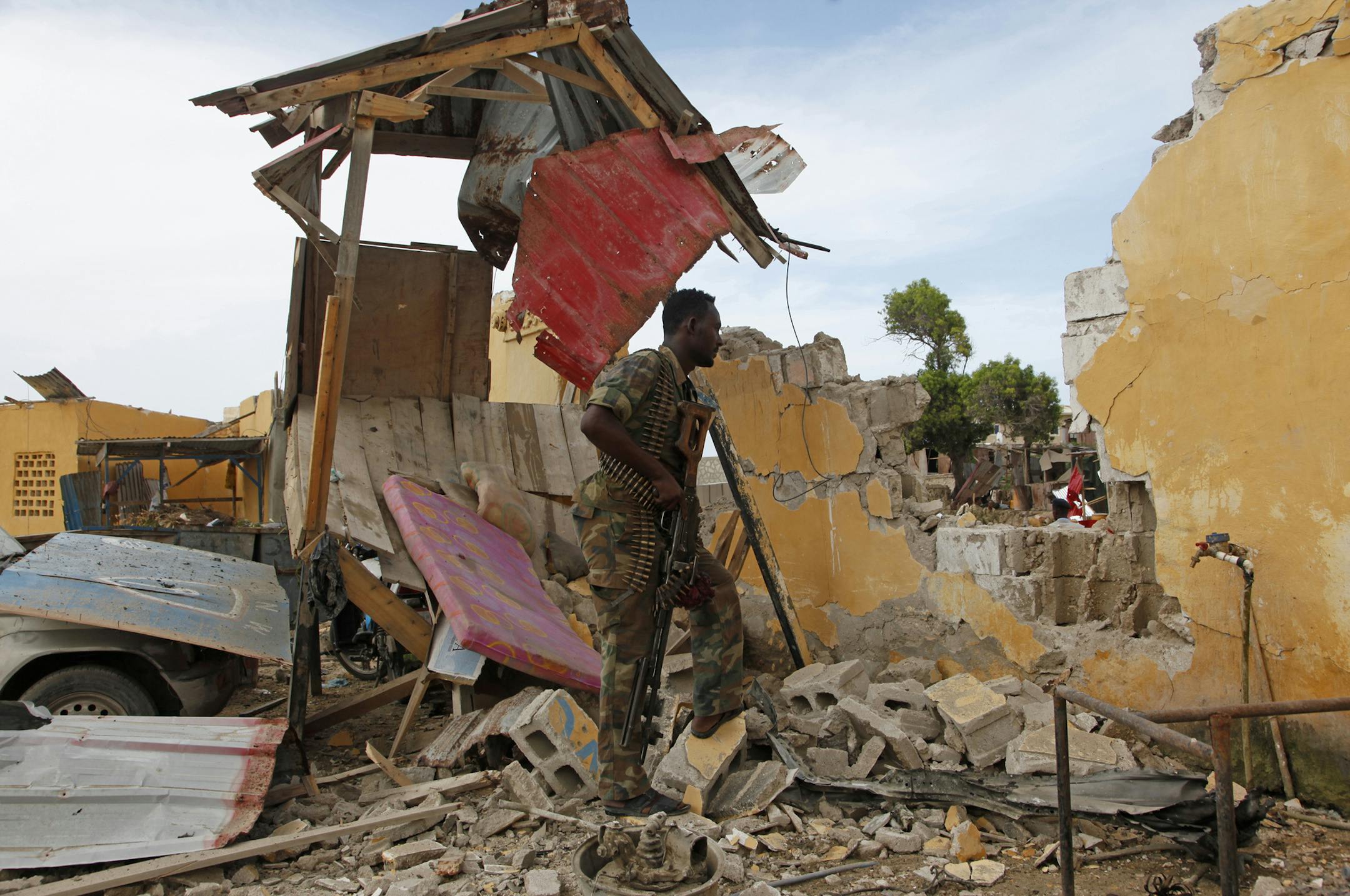 A Somali soldier stands near a destroyed building outside the police traffic station in Mogadishu, Somalia, Monday, May, 9, 2016. A Somali police official says a suicide car bomber struck the entrance of the East African country's traffic police headquarters in the capital, killing four people and injuring others. Somalia's Islamic extremist rebels, al-Shabab, claimed responsibility for the attack, which shattered a period of calm in the seaside city. (AP Photo/Farah Abdi Warsameh)