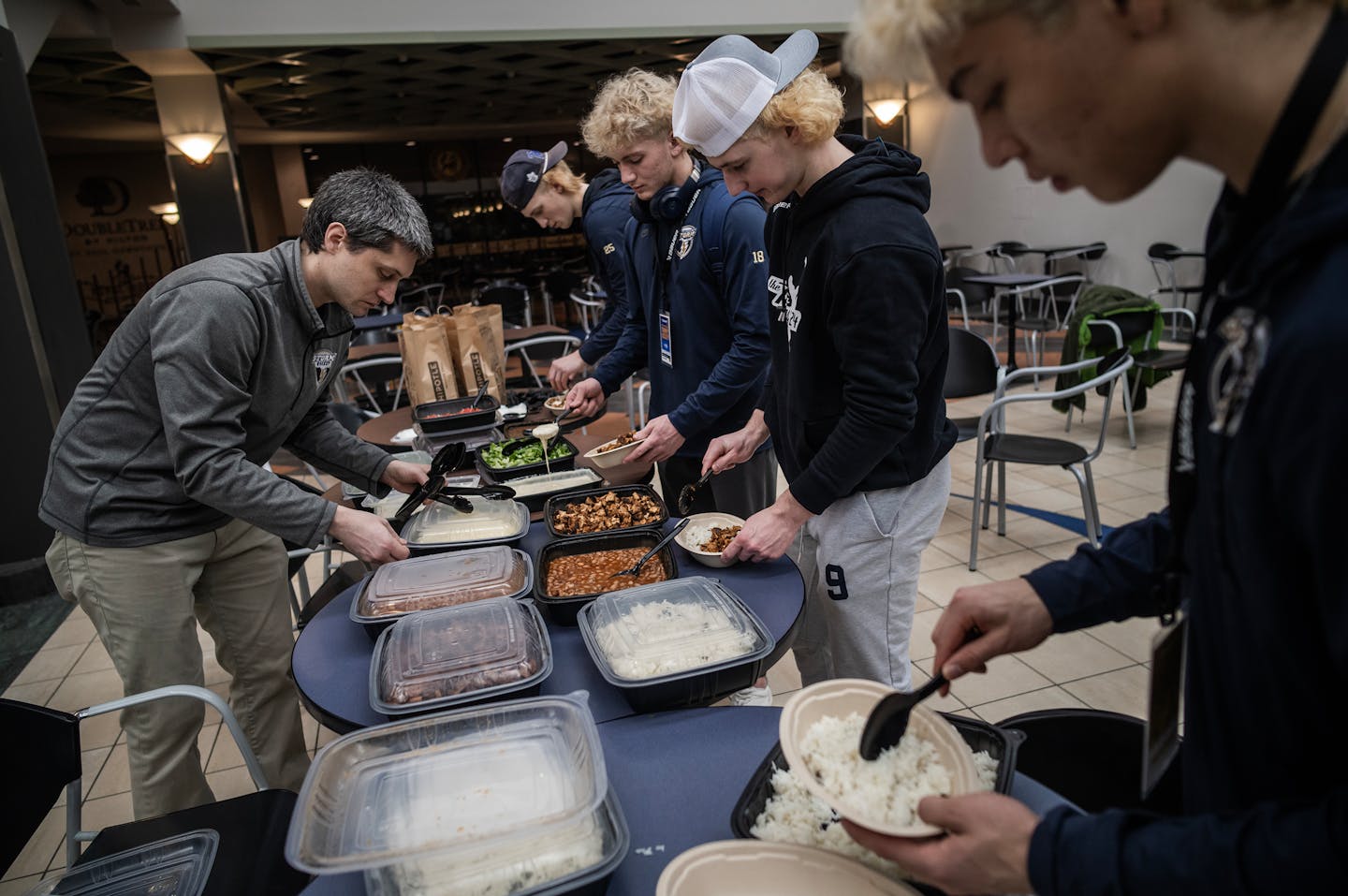 Head coach Sean Bloomfield helps set some lunch for his team on Thursday.