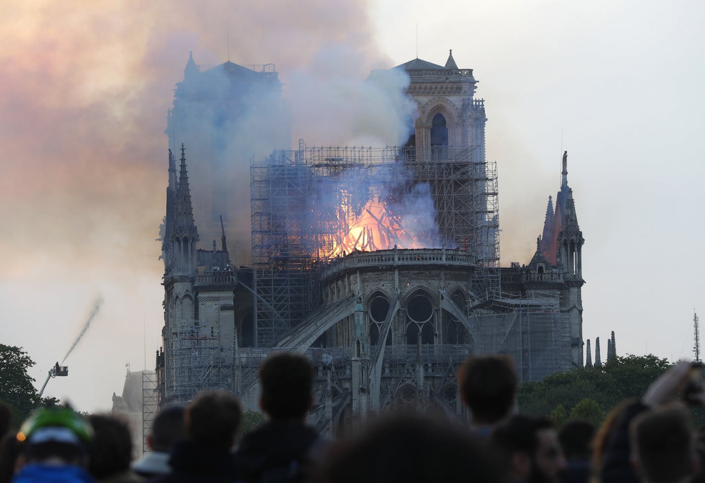 People watch as flames and smoke rise from Notre Dame cathedral as it burns in Paris on Monday.