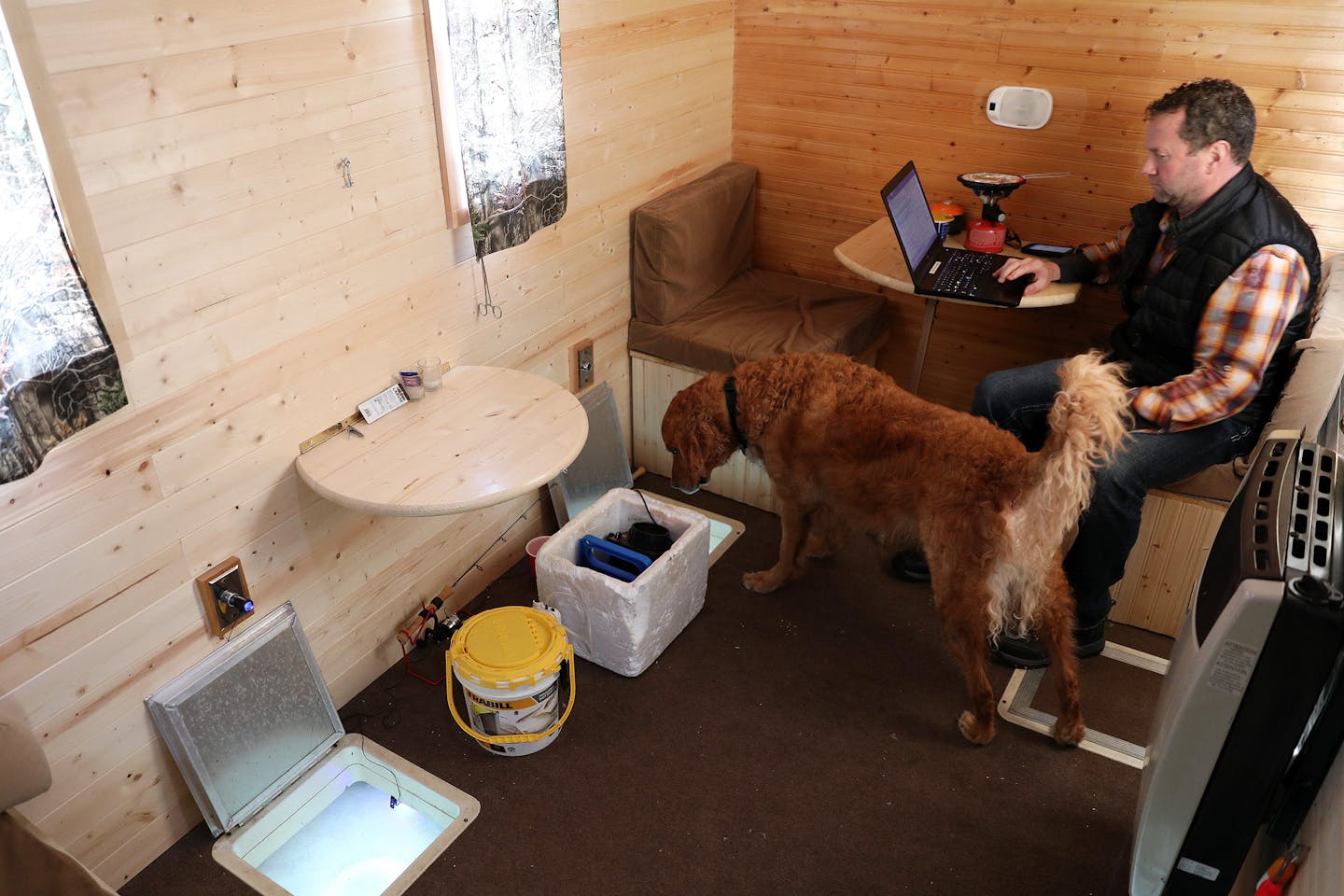 Darrin Stuhr of Eden Prairie worked from his laptop alongside his dog Baylor, a 4-year-old golden retriever, in his ice fishing shelter Thursday at Lake Minnetonka. ] ANTHONY SOUFFLE &#xef; anthony.souffle@startribune.com Minnesota Department of Natural Resources conservation officers Brent Grewe and Leah Weyandt talked with anglers about the upcoming deadline to remove their ice fishing shelters Thursday, March 1, 2018 on Lake Minnetonka in Wayzata, Minn.