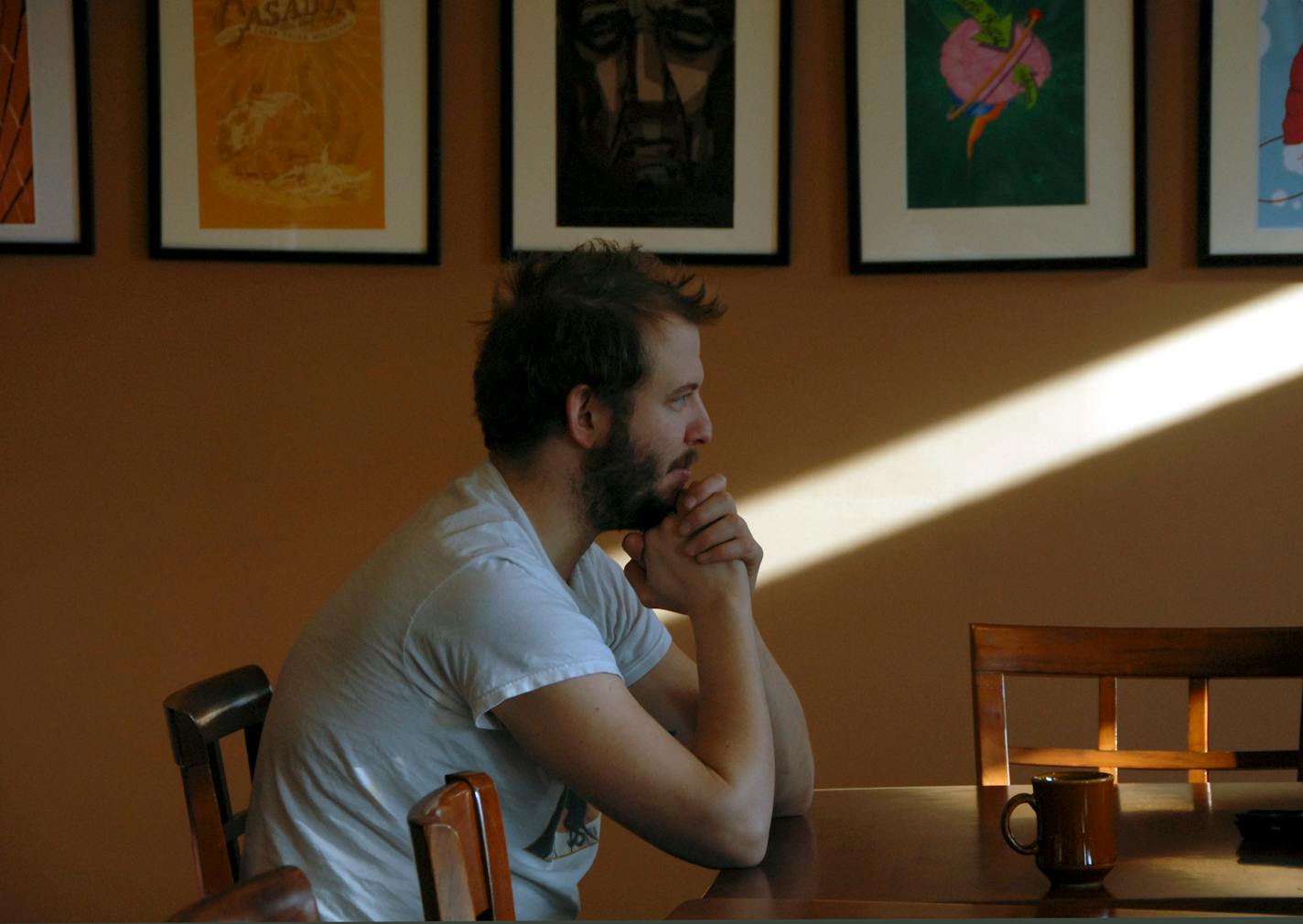 Justin "Bon Iver" (NOTE--please check to see what Chris is using for his name) drank coffee near posters of acts that have played at Racy D'Elenes, a coffeehouse on the Chippewa River in Eau Claire. Bon Iver is on the wall a couple of times.