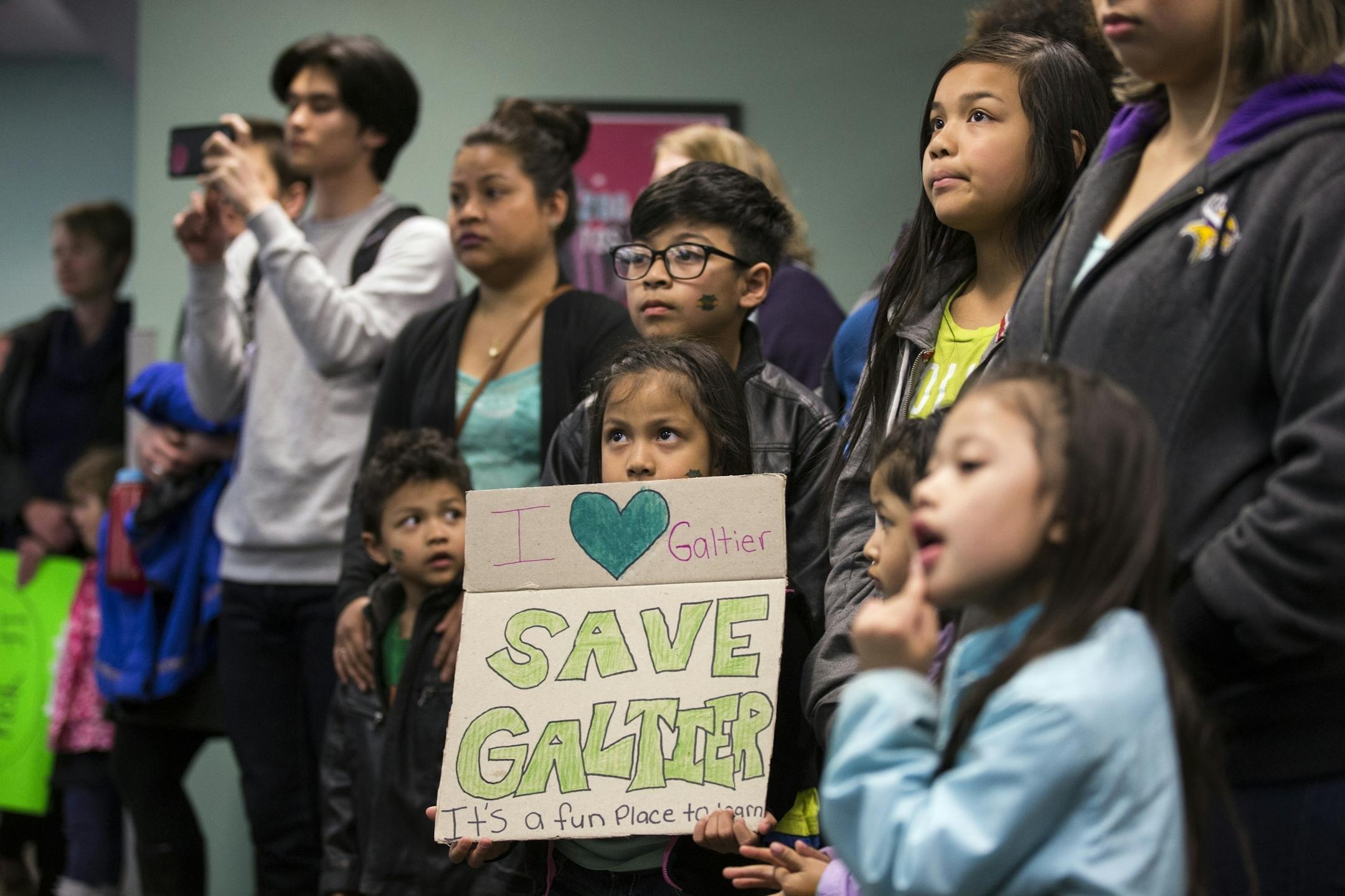 Galtier Community School first grader Jalyssa Sengdara, 7, center, holds a sign during the public comment portion of a St. Paul School Board meeting.