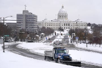 A plow truck made its way up the hill in front of the Cathedral of St. Paul on Wednesday, with the State Capitol building in the backdrop. More snow i