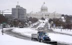 A plow truck made its way up the hill in front of the Cathedral of St. Paul on Wednesday, with the State Capitol building in the backdrop. More snow i