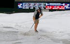 A Target Field grounds crew worker pushes water off the tarp during a rain delay prior to a baseball game between the Minnesota Twins and the Seattle 