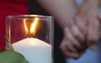 A candle representing one of the victims of a deadly shooting with multiple fatalities at Santa Fe High School burns in a memorial at a vigil Friday, 