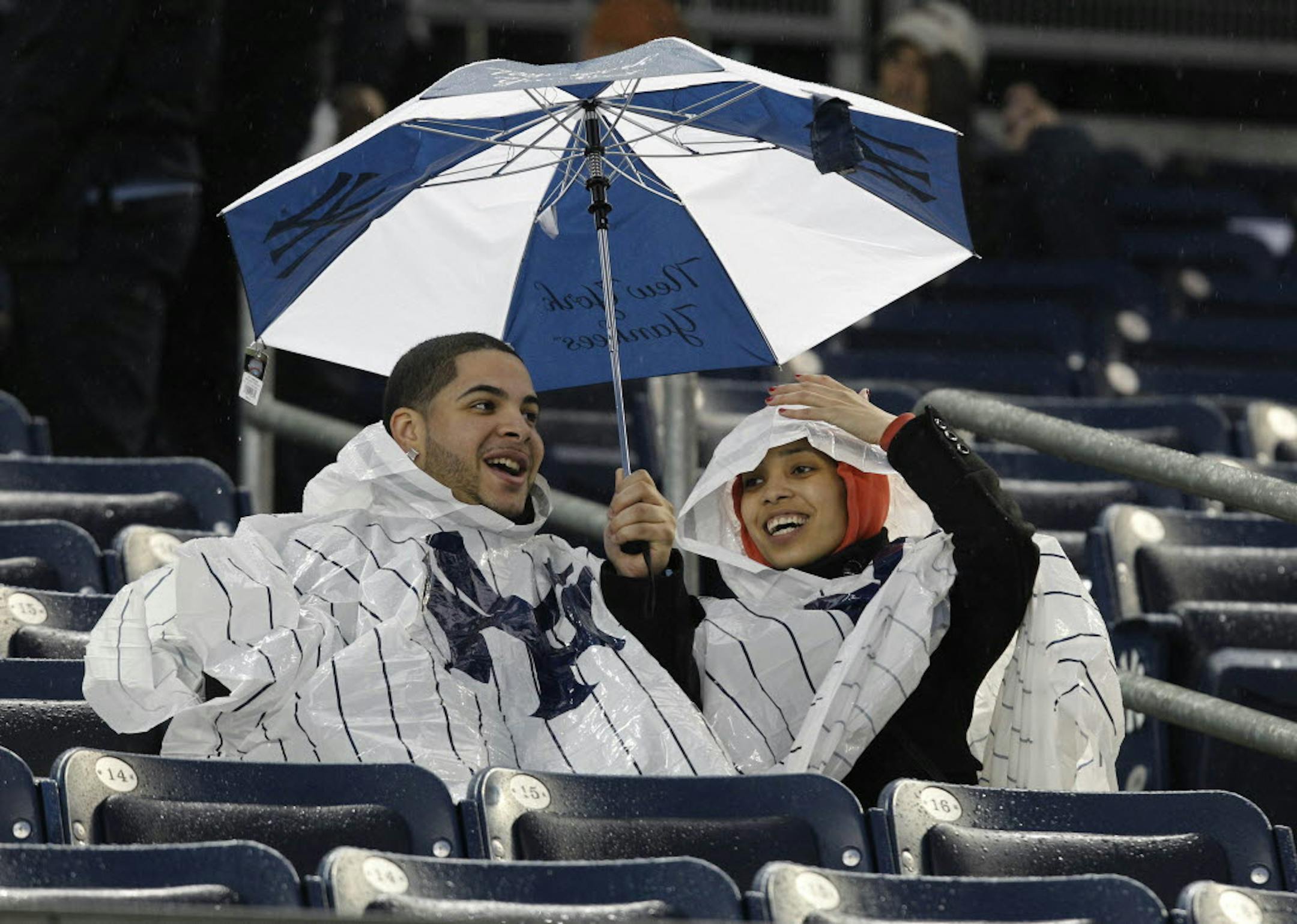Thomas Taveras and Liz Mateo wait out a rain delay before a baseball game between the Twins and the New York Yankees at Yankee Stadium. The game was postponed.