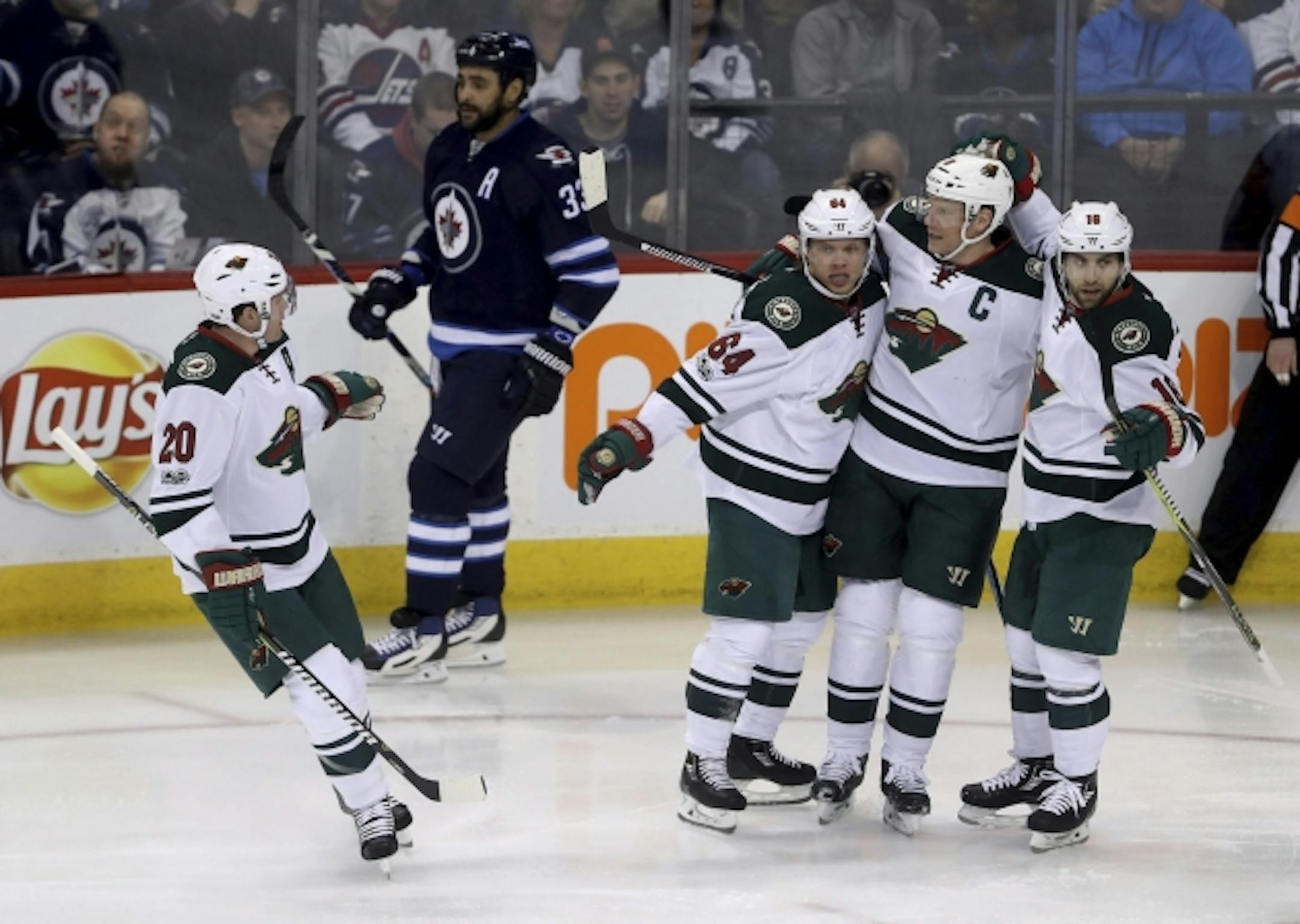 Minnesota Wild's Ryan Suter (20), Mikael Granlund (64), Mikko Koivu (9) and Jason Zucker (16) celebrate after Granlund scored, as Winnipeg Jets' Dustin Byfuglien (33) skates past during the first period of an NHL hockey game Tuesday, Feb. 28, 2017, in Winnipeg, Manitoba. (Trevor Hagan/The Canadian Press via AP)