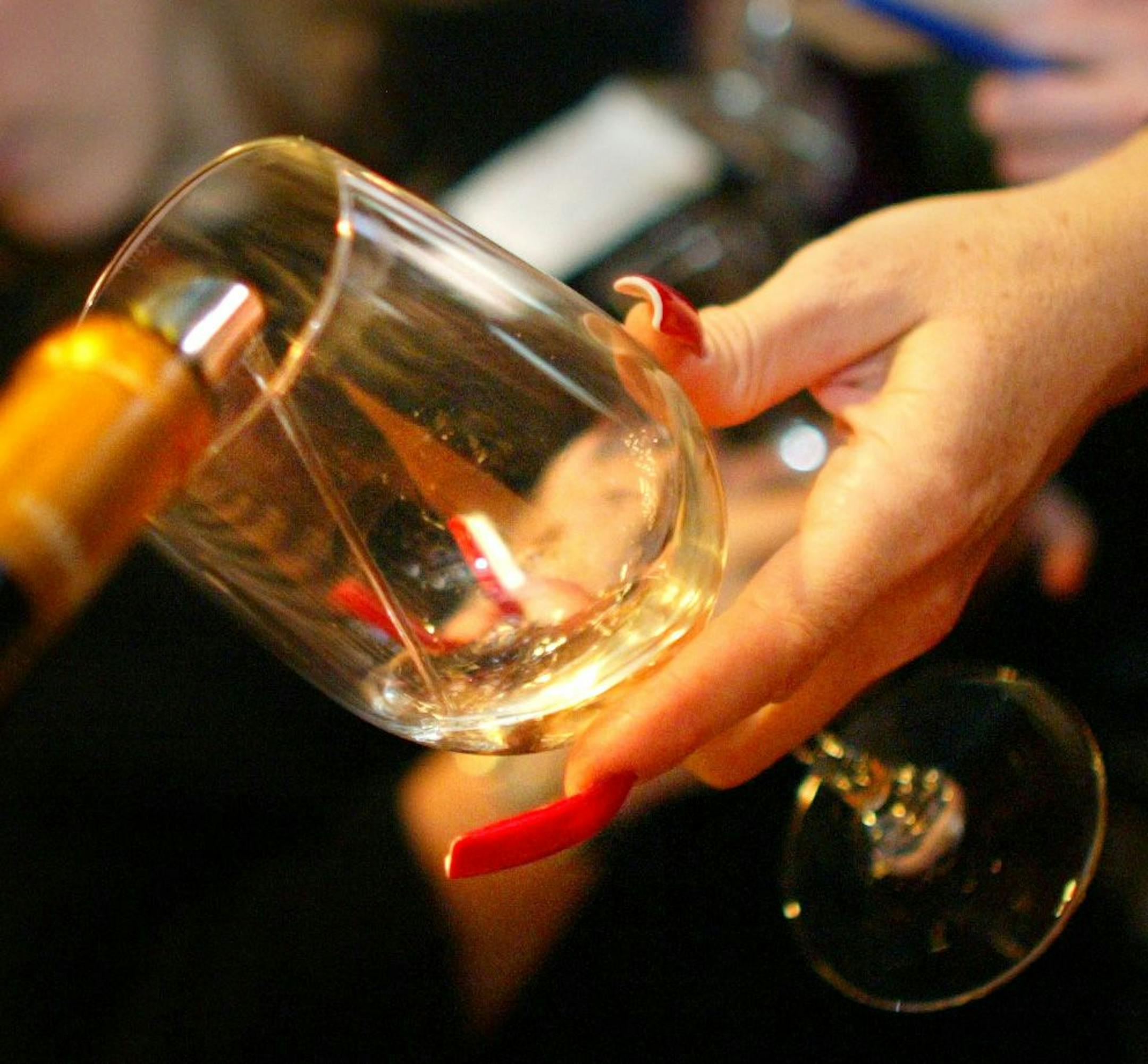RENEE JONES SCHNEIDER � reneejones@startribune.com Wine specialist Robert Croce pours white wine into a woman's glass during Uncorked at Rossi's Blue Star Room in Minneapolis.